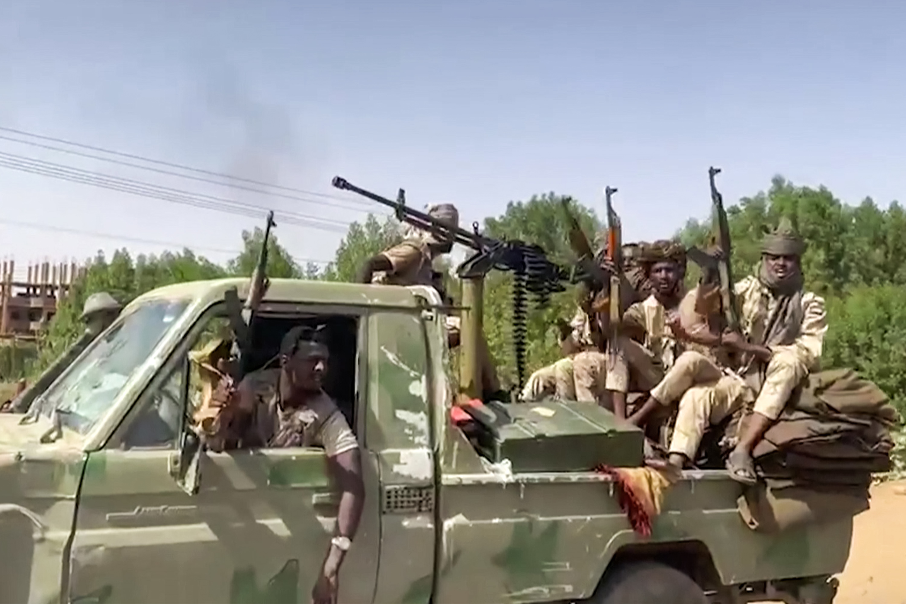 A green truck of RSF soldiers whooping and cheering