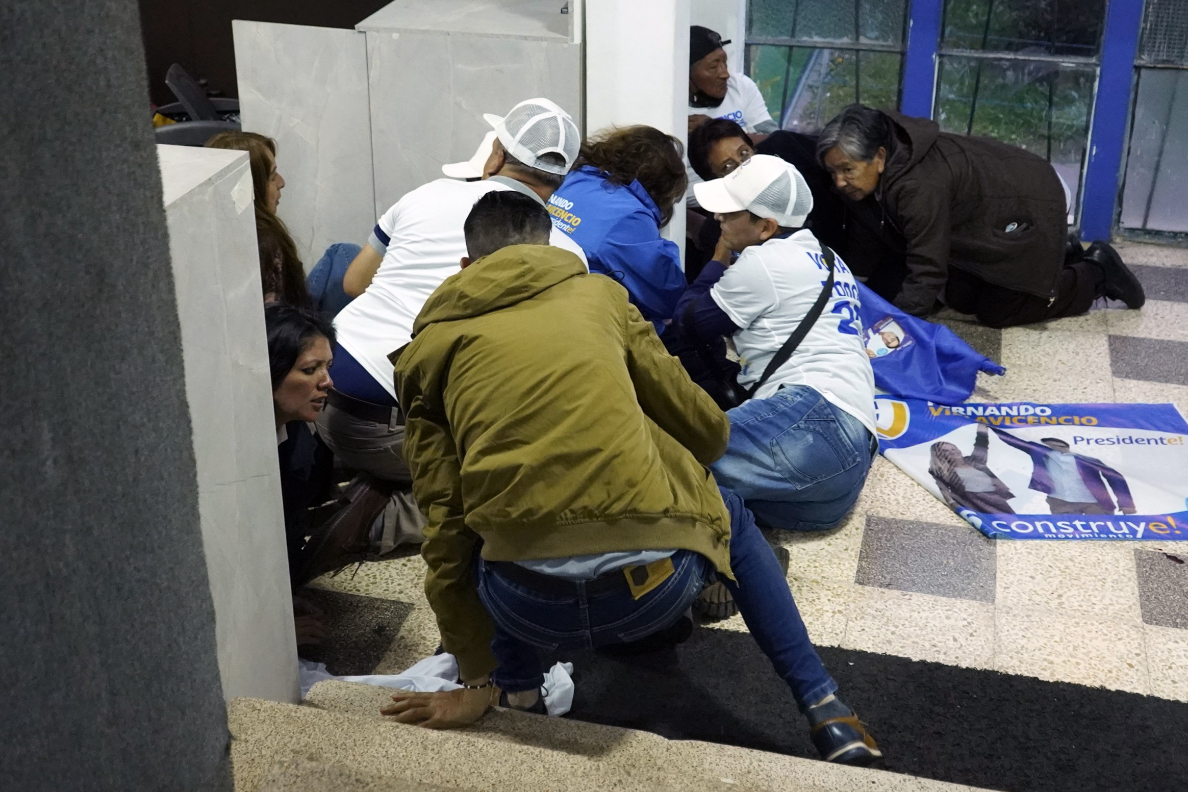 People take cover after shots were fired at the end of a rally of Ecuadorian presidential cadidate Fernando Villavicencio in Quito, on August 9, 2023. - Ecuadorian presidential candidate Fernando Villavicencio was shot dead after holding a rally in Quito on Wednesday evening, local media reported, citing Interior Minister Juan Zapata. Mr. Villavicencio, a 59-year-old journalist, was one of eight candidates in the August 20 presidential election. (Photo by STRINGER / AFP)