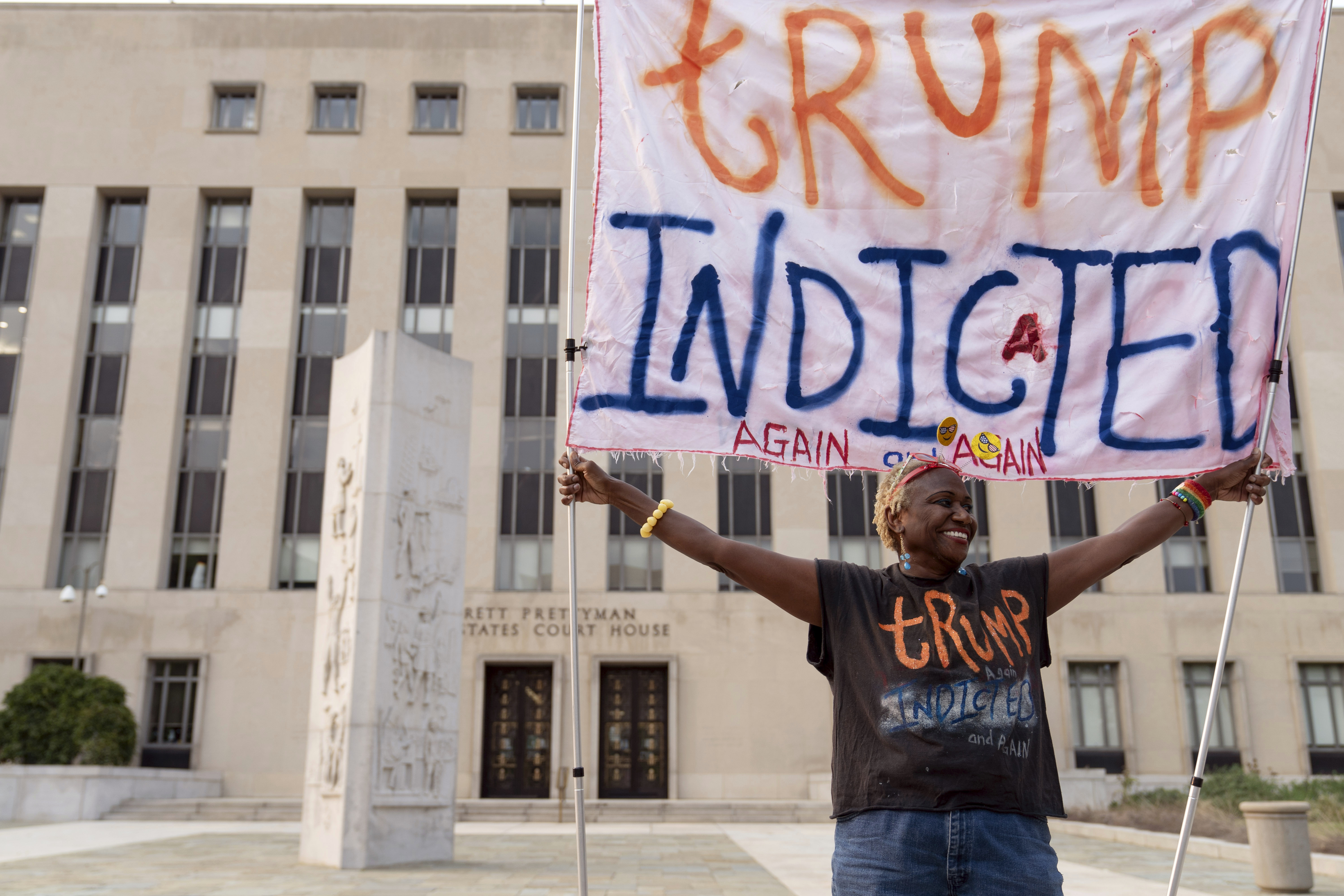 A woman holds up a hand-painted sign that reads, "Trump indicted."