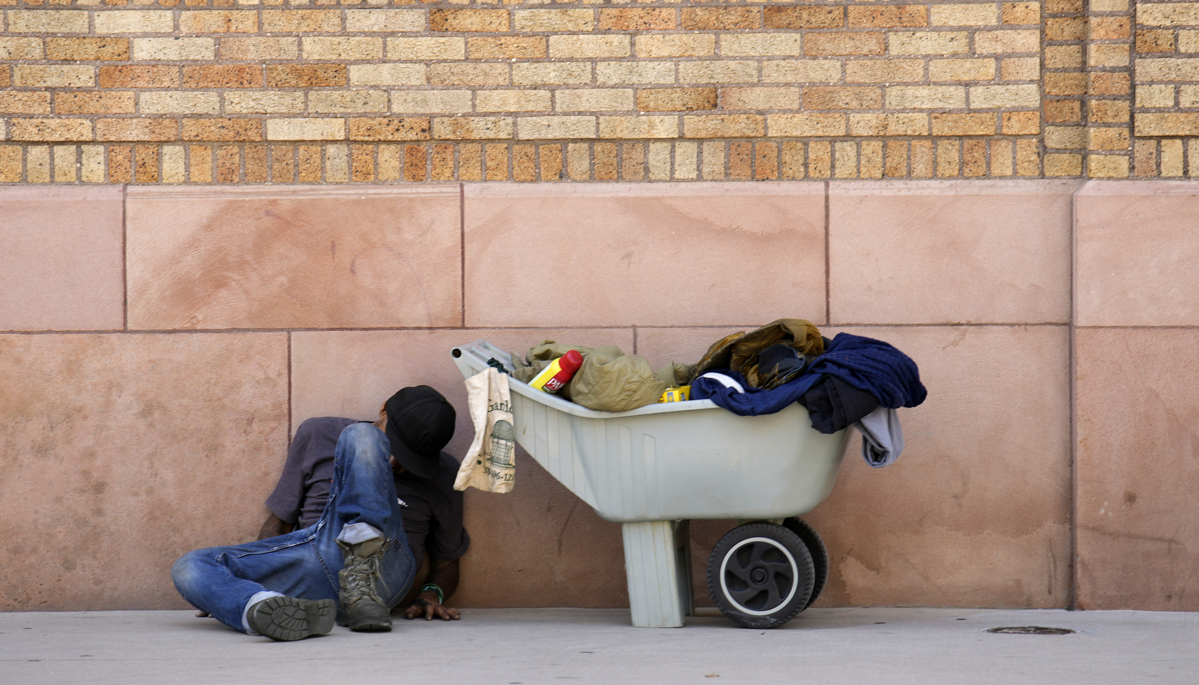 A man sleeps against the wall of a building along 14th Street as temperatures soar into the low 90s Friday, Aug. 4, 2023, in downtown Denver. (AP Photo/David Zalubowski)