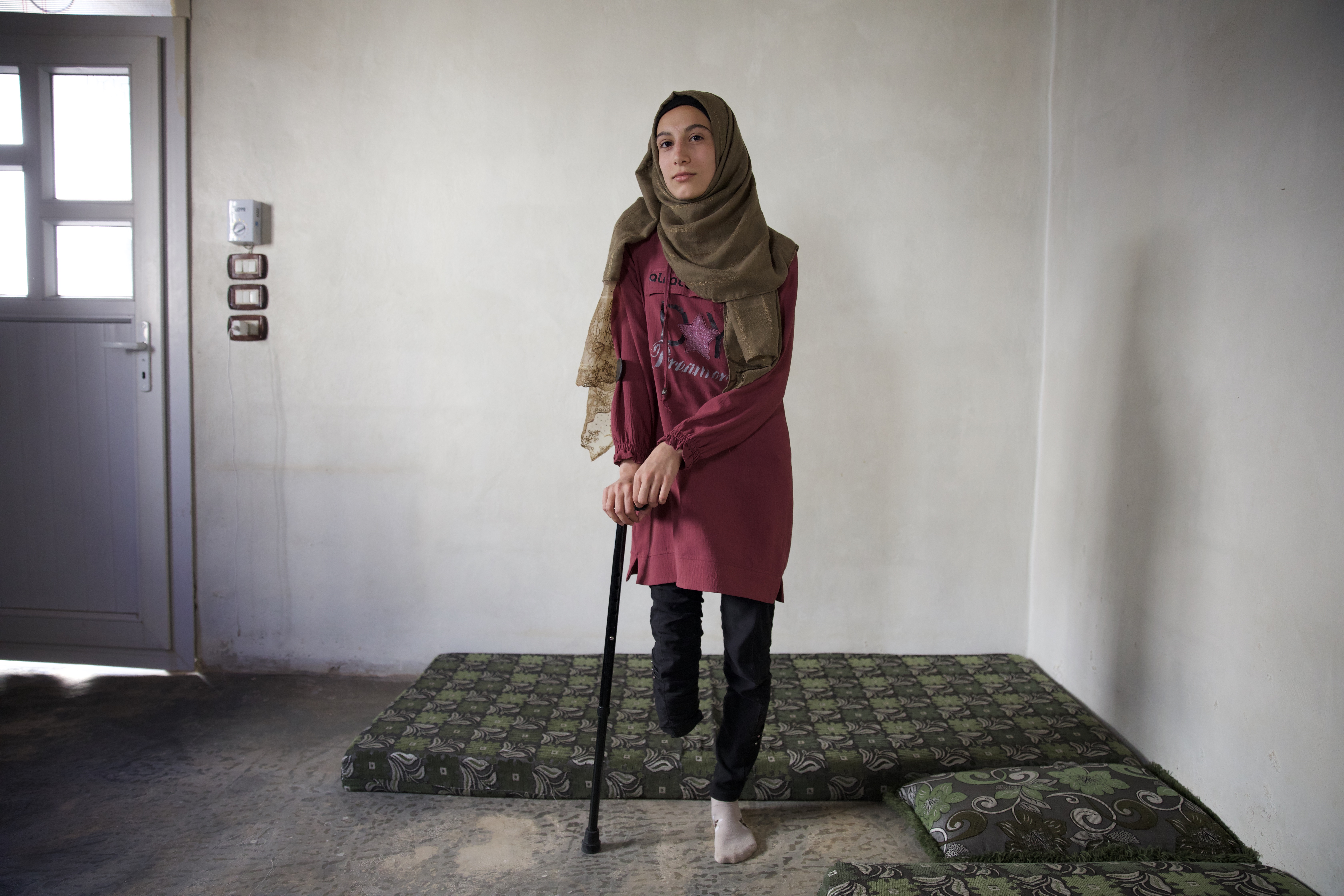 Rima stands leaning on her crutch
