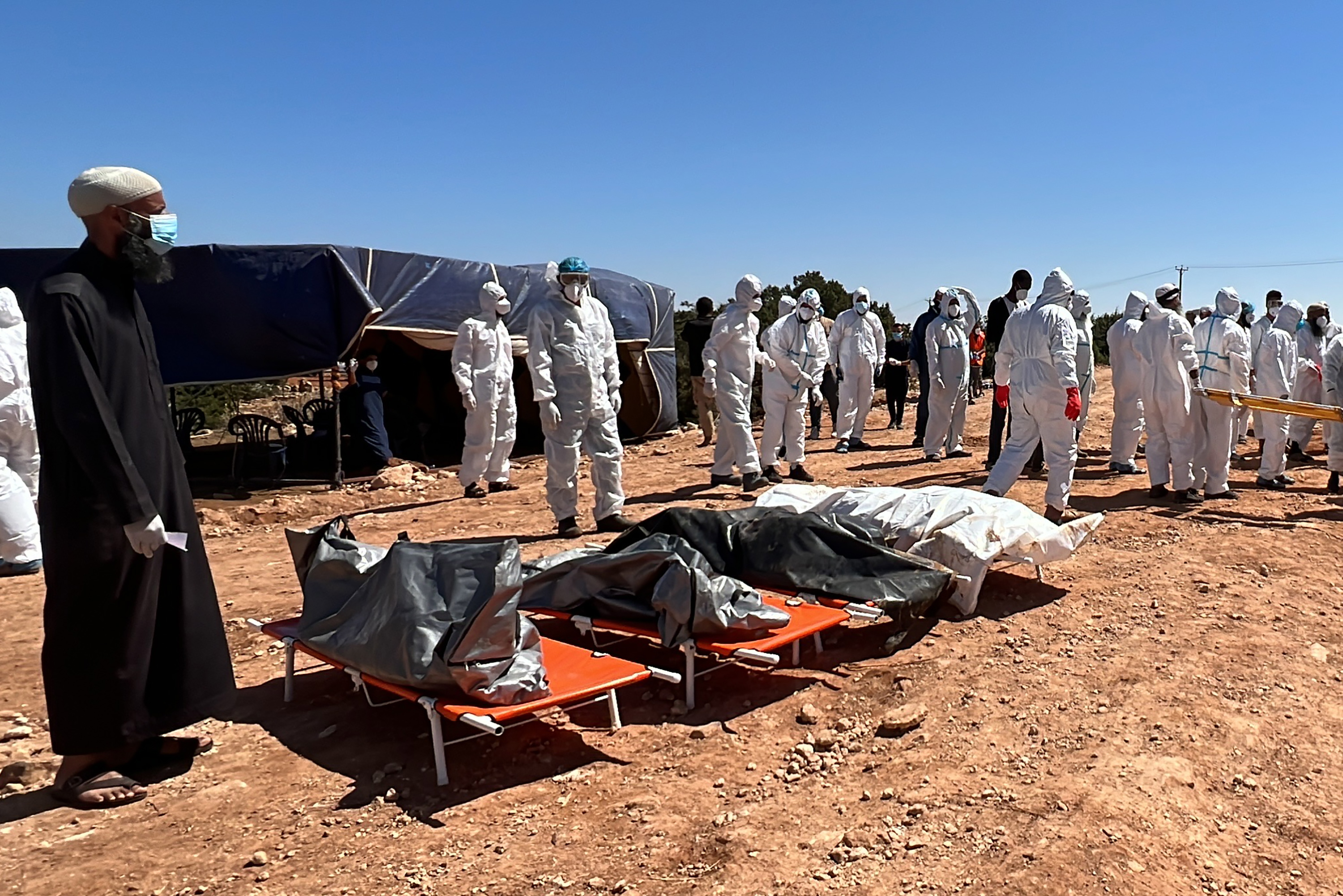 Rescuers stand near bodies of victims who died after Storm Daniel swept across eastern Libya, before burying the victims in mass graves, in the port city of Derna
