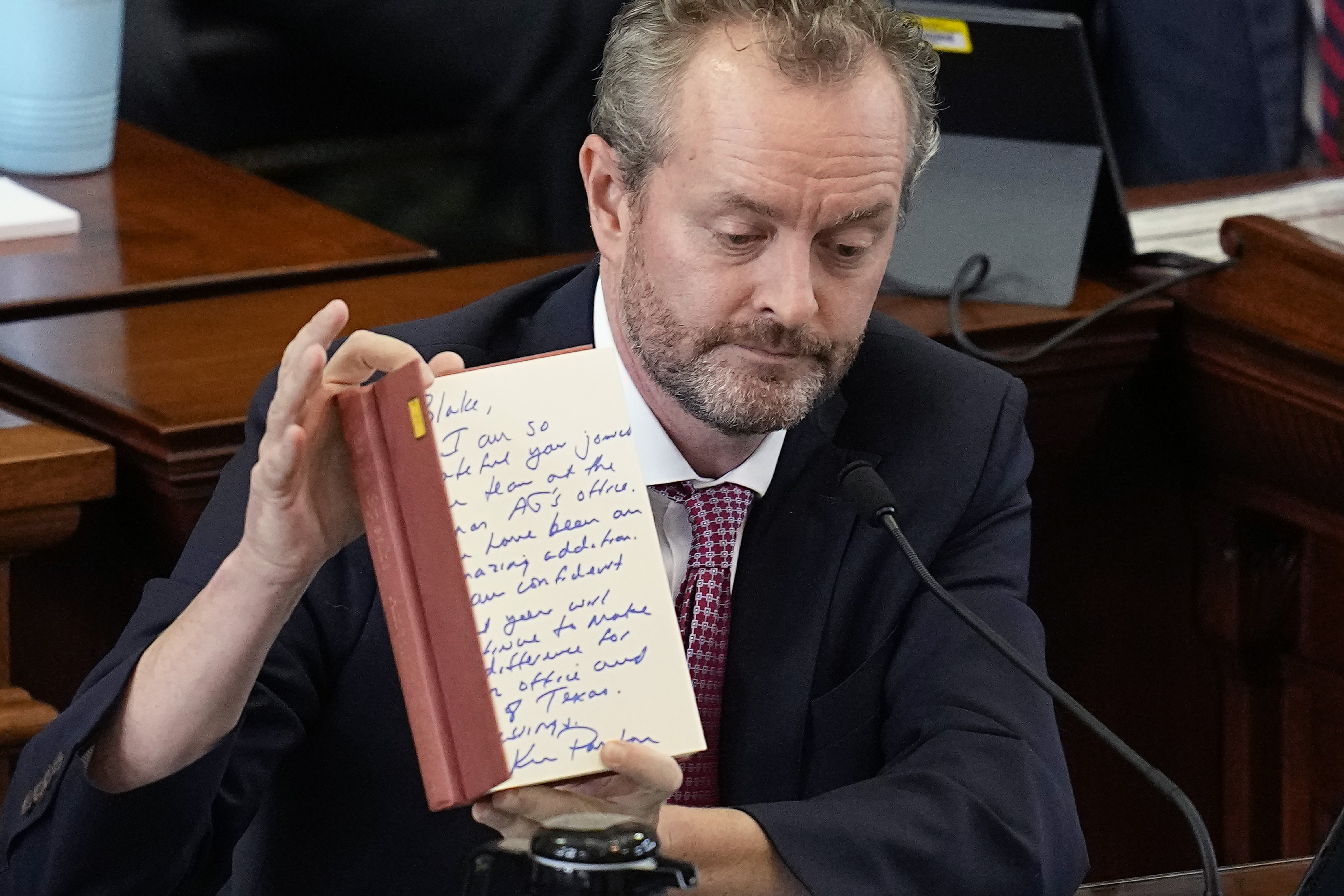 Whistleblower Blake Brickman shows a book with an inscription from Texas Attorney General Ken Paxton as he testifies during the impeachment trial for Paxton in the Senate Chamber at the Texas Capitol, Wednesday, Sept. 13, 2023, in Austin, Texas.