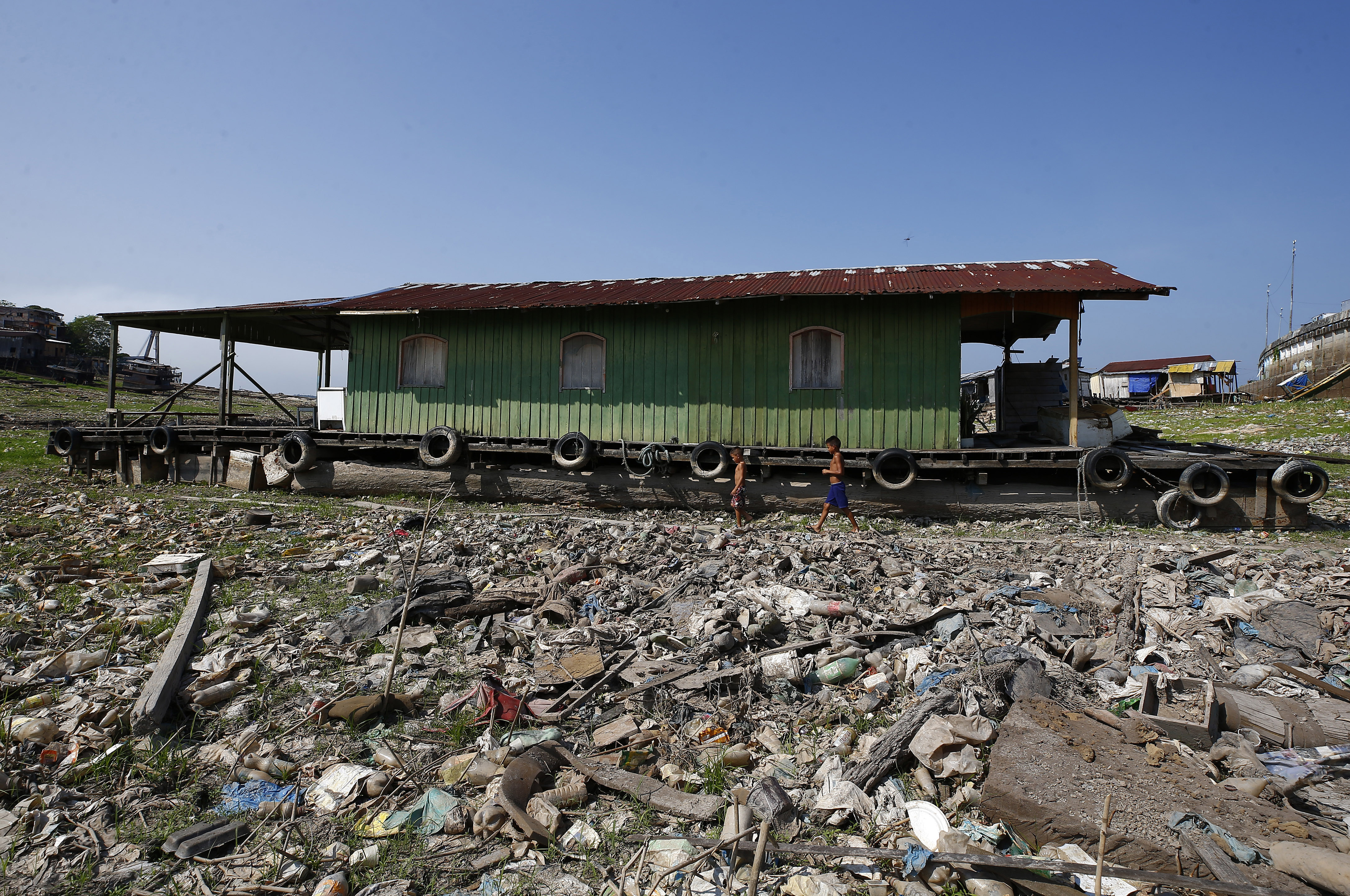 Boys walk next to a floating home stranded on what used to be the water´s edge of the Negro river