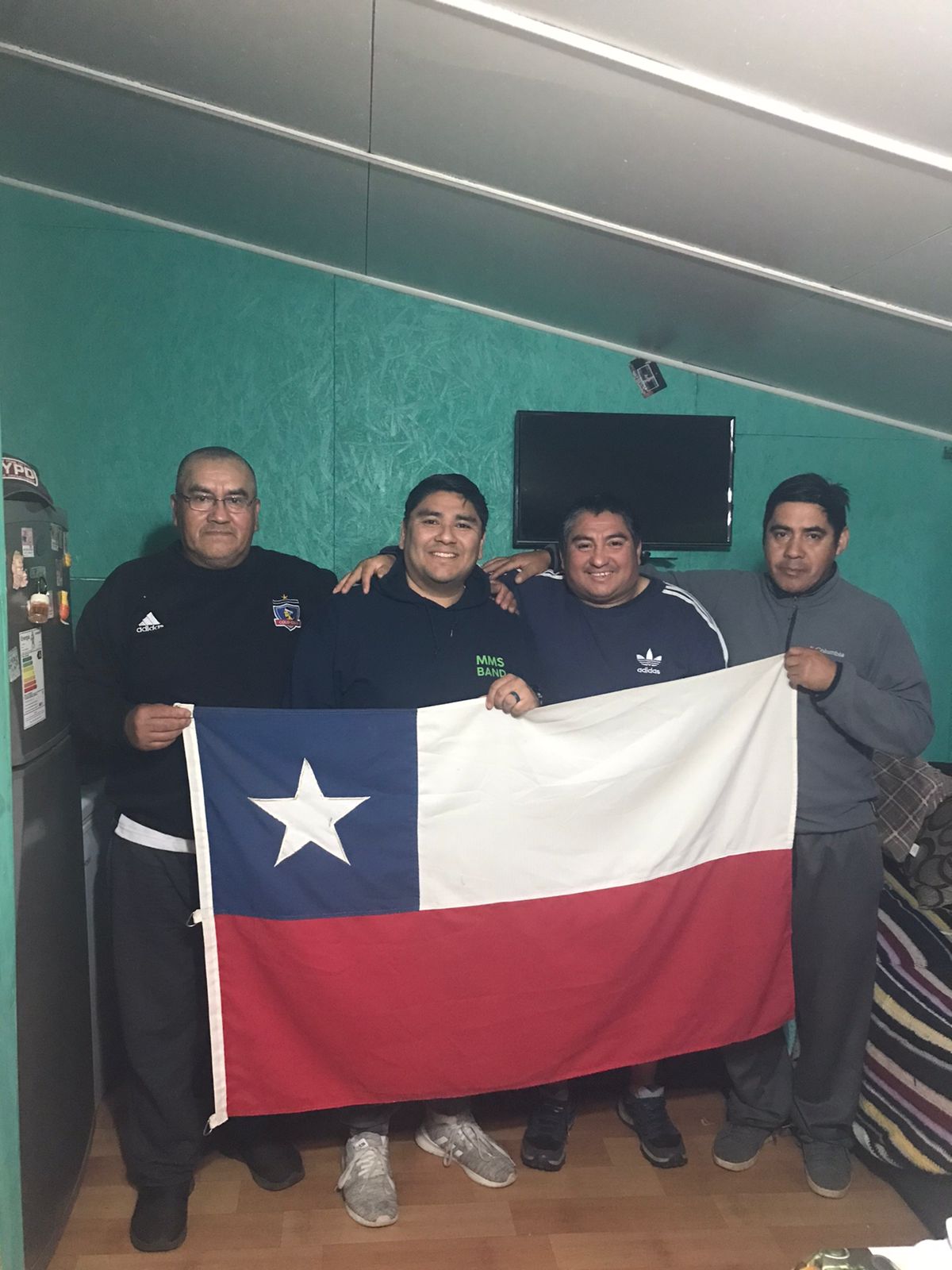 Four brothers hold up a Chilean flag at a reunion.