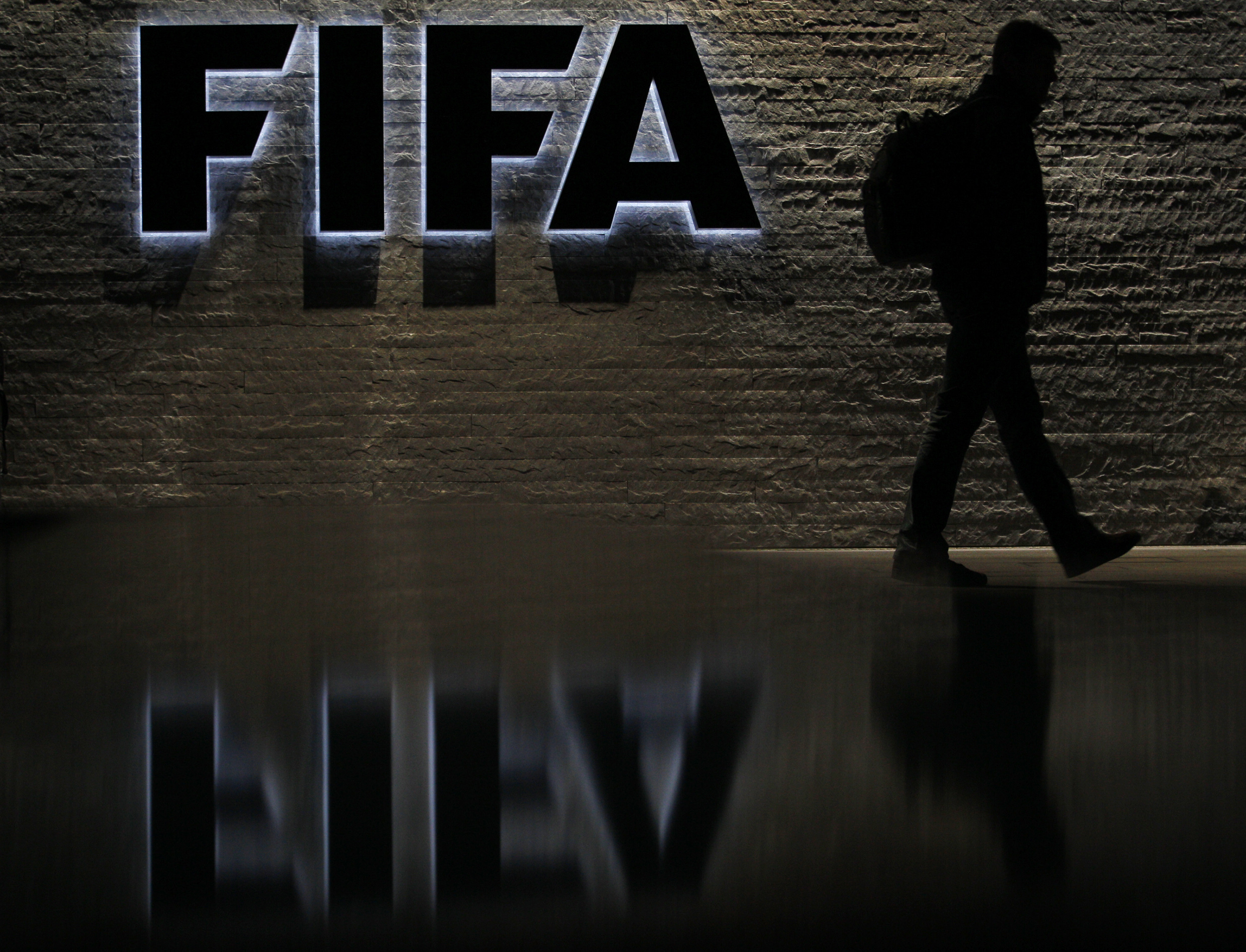 A man is silhouetted as he makes his way past the main entrance of FIFA headquarters.