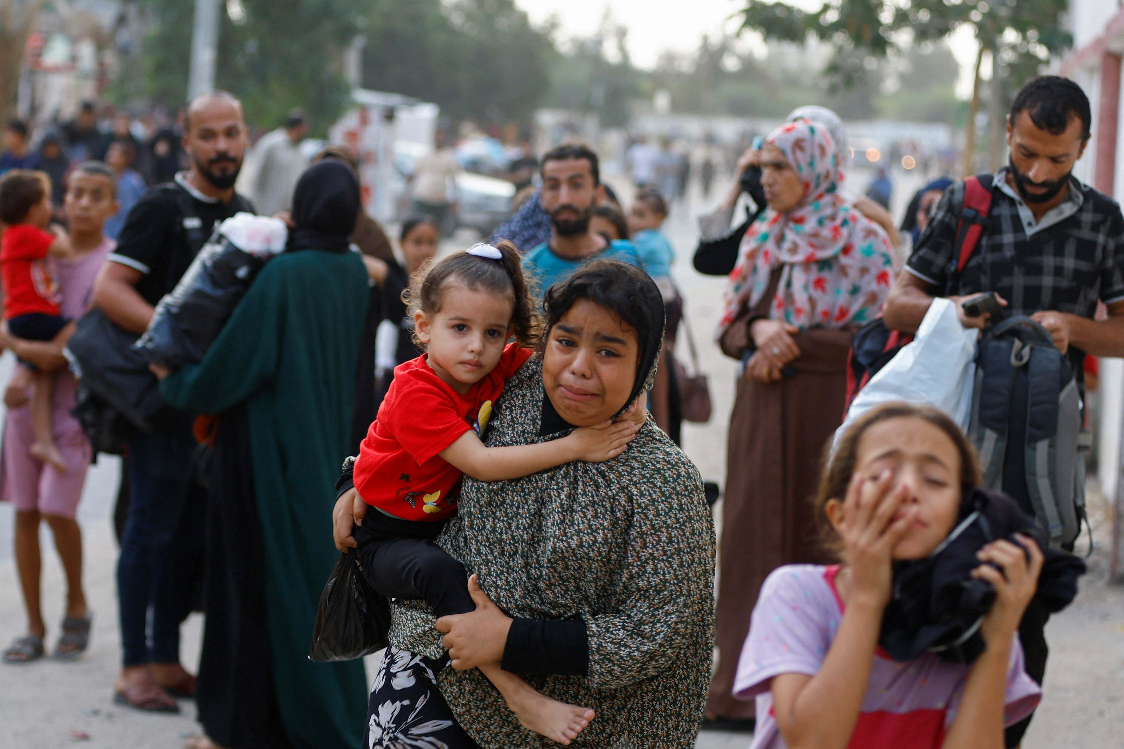 A young child sits on his mother's hip as she and others flee through the streets of the Gaza Strip.