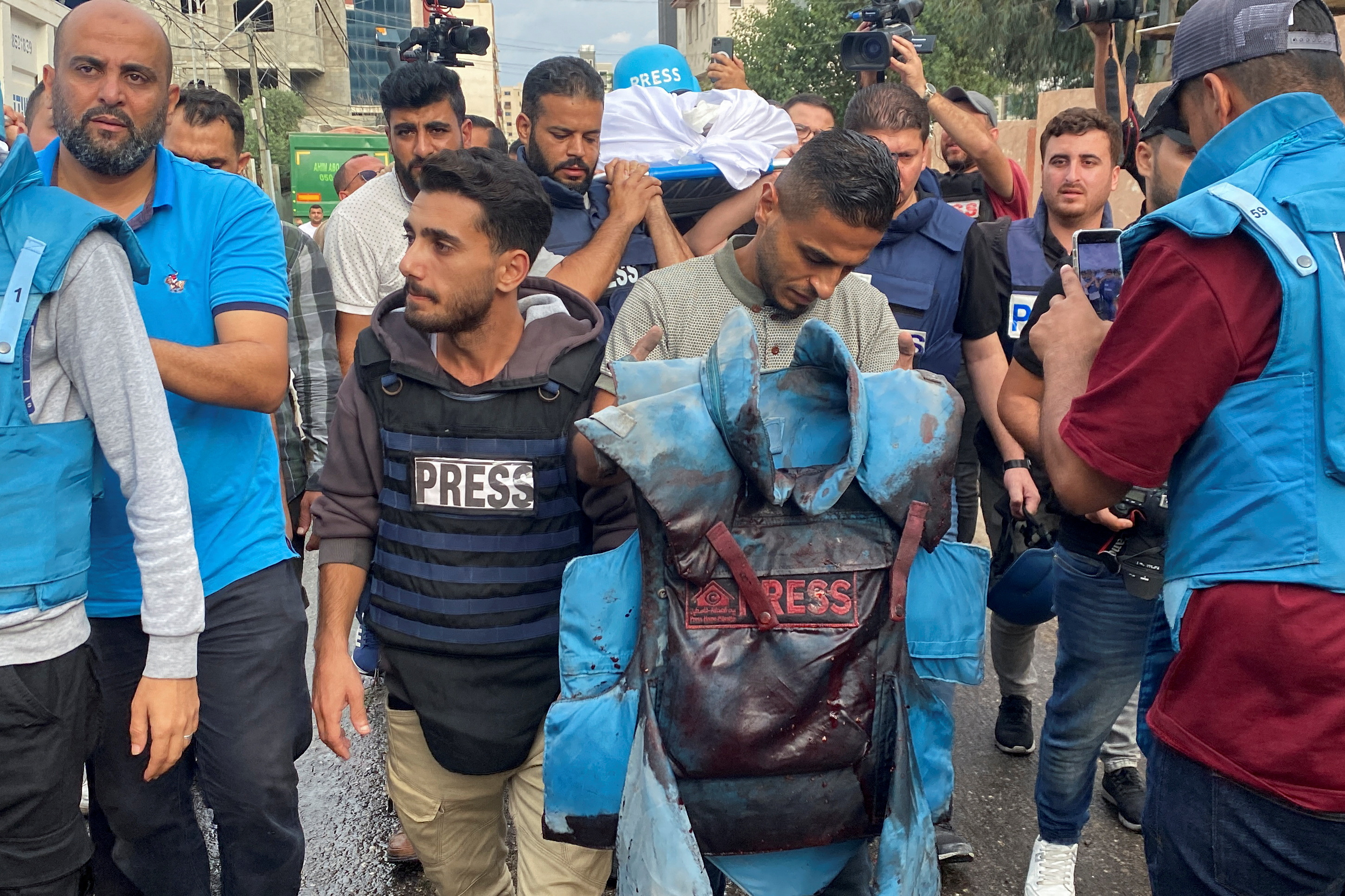 A colleague carries a blood-stained flak jacket belonging to Palestinian journalist Mohammed Soboh, who was killed along with two other journalists when an Israeli missile hit a building while they were outside reporting, at a hospital in Gaza City