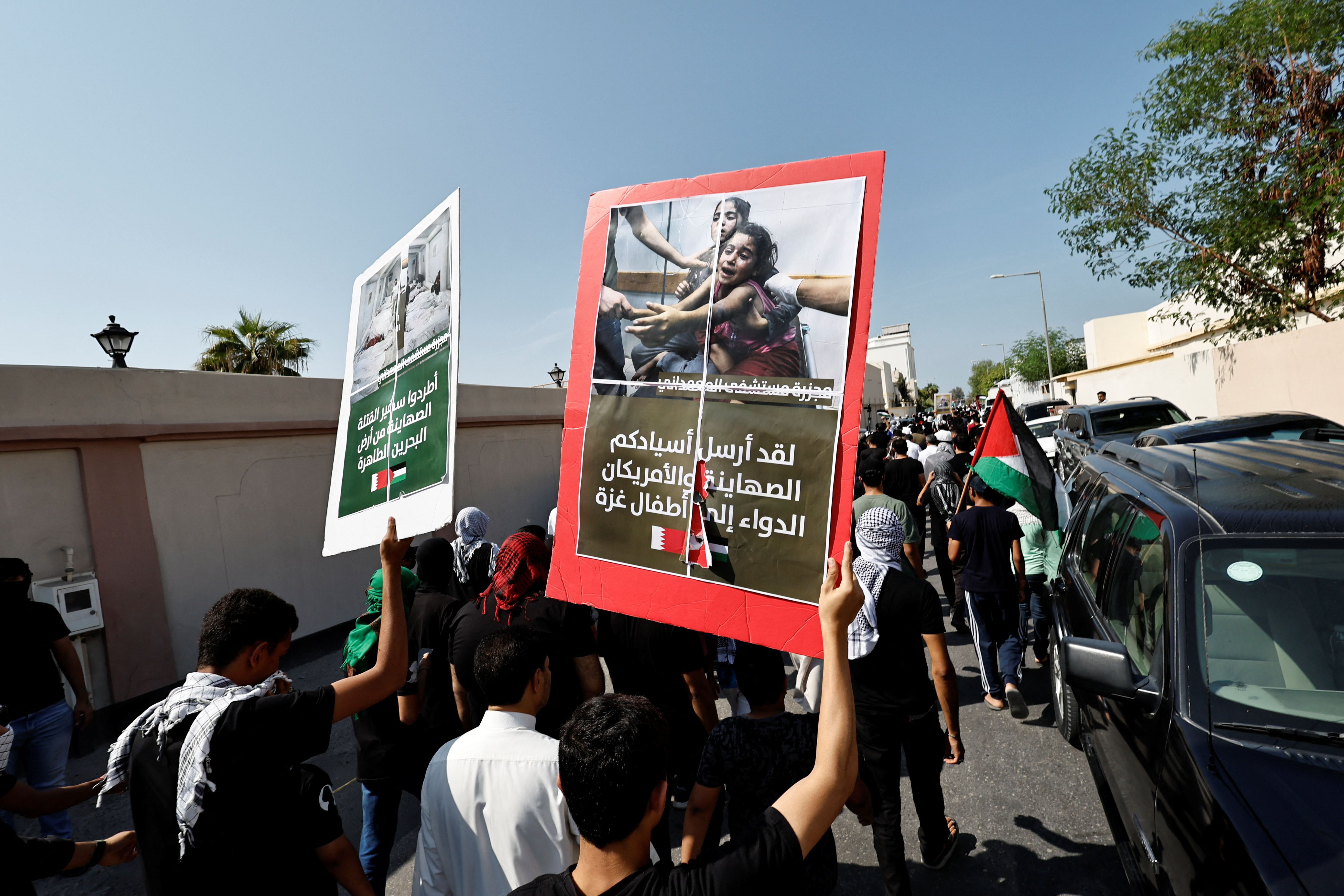 Protesters holding photos of aftermath from Gaza raids as they march during a protest in support of Palestinians after Friday prayers in the village of Diraz, Bahrain