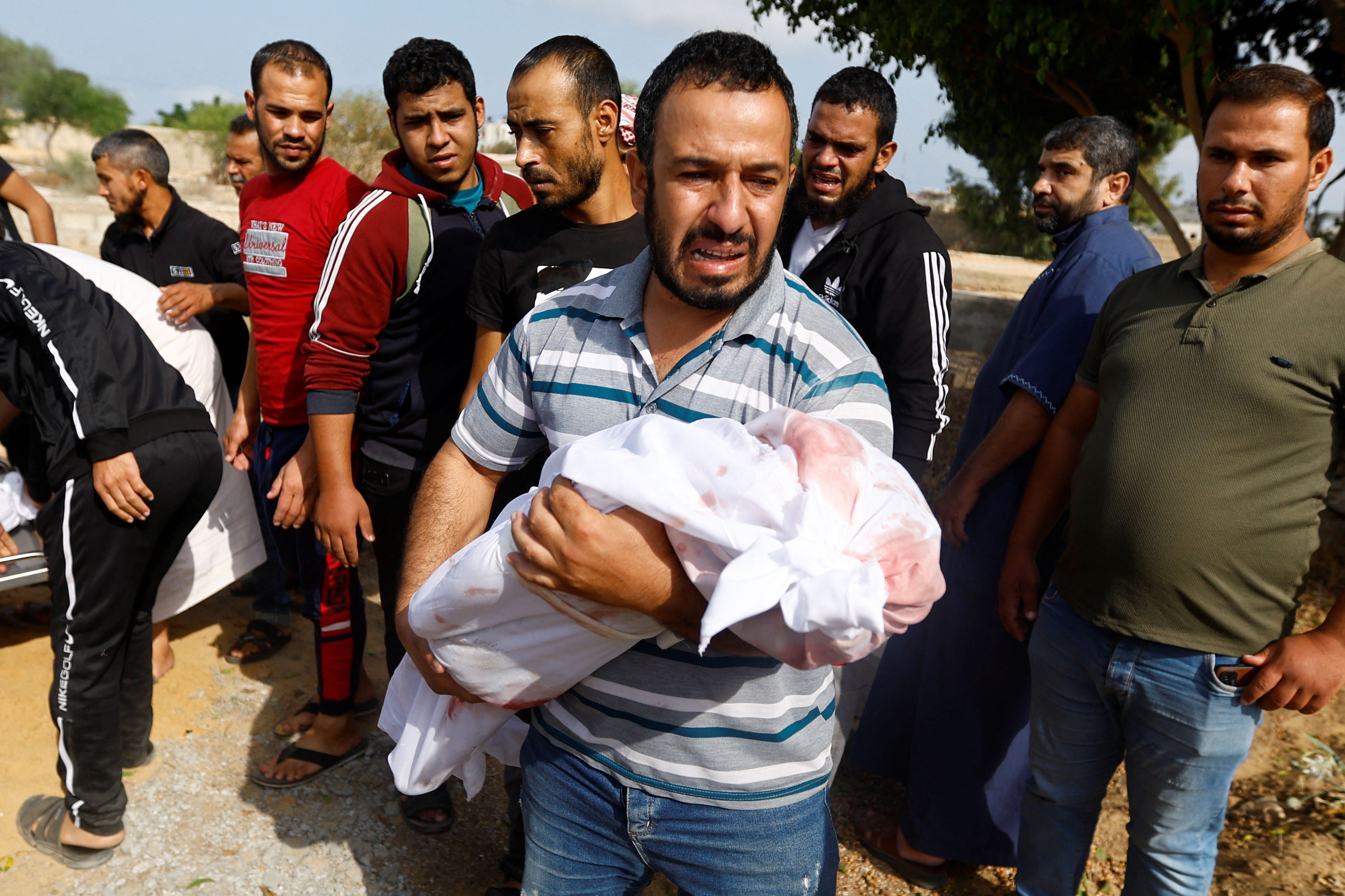 A mourner carries the body of a child, during the funeral of Palestinians from al-Astal family, who were killed in Israeli strikes, in Khan Younis in the southern Gaza Strip