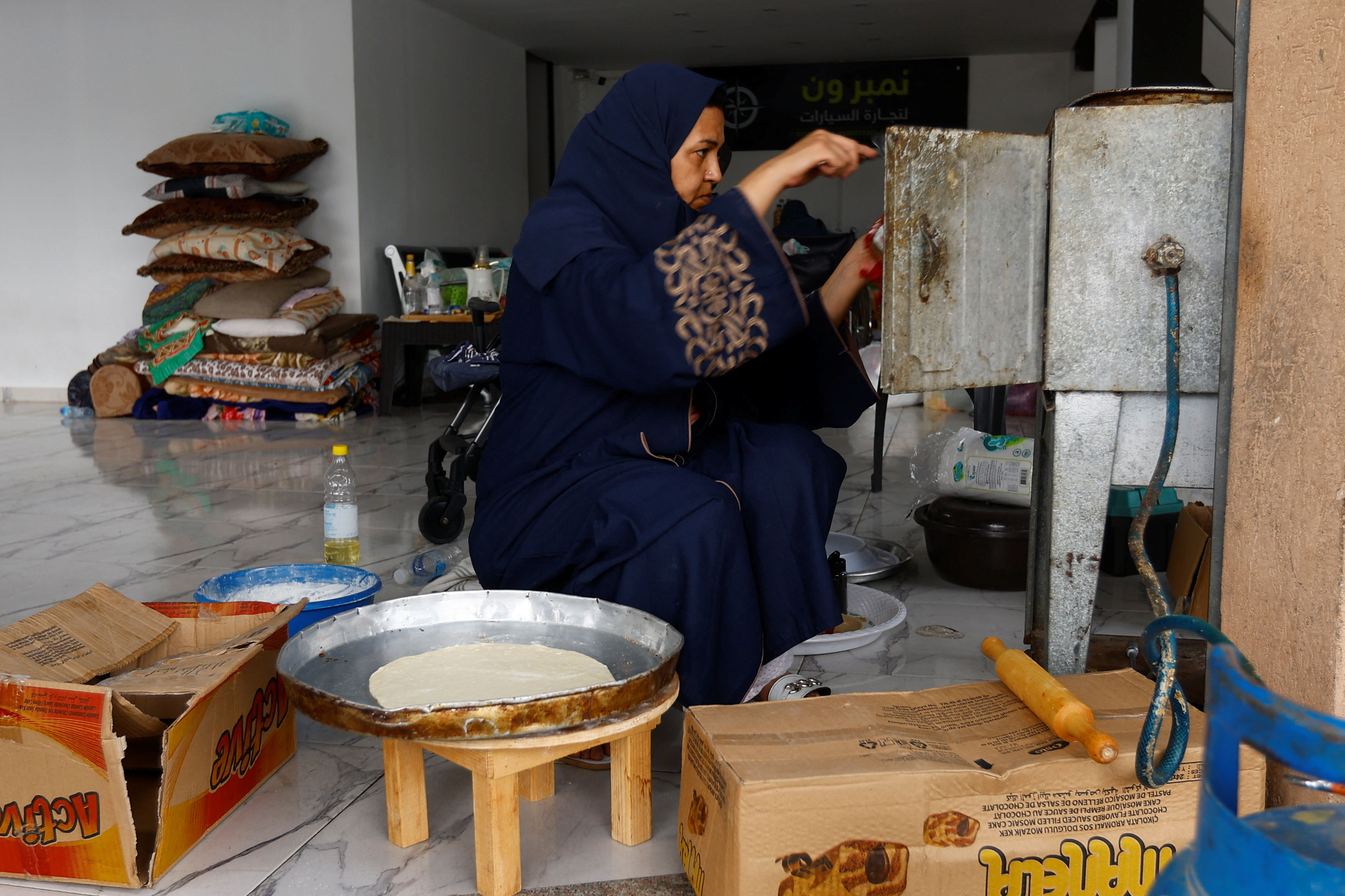 Palestinian woman Kholoud Qdeih, who fled her house that is located near the border with Israel and now lives with 20 members of her extended family in the basement of a building, prepares the dough as she bakes, amid the ongoing conflict with Israel, in Khan Younis in the southern Gaza Strip