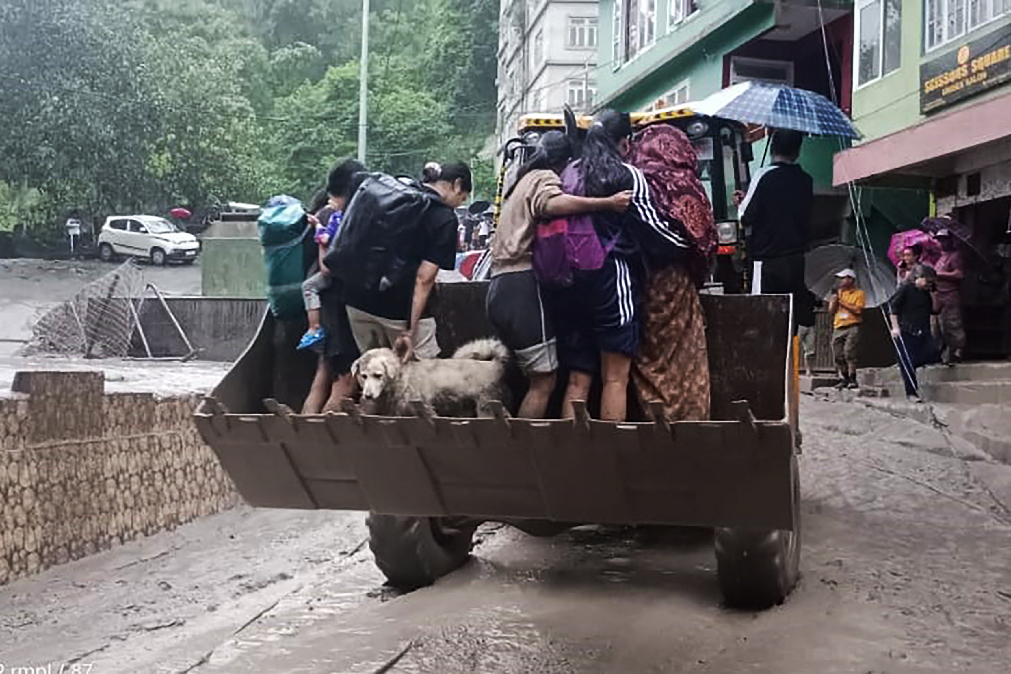 Residents are being evacuated on a backhoe loader in Muguthang, in India's Sikkim state following a flash flood caused by intense rainfall.