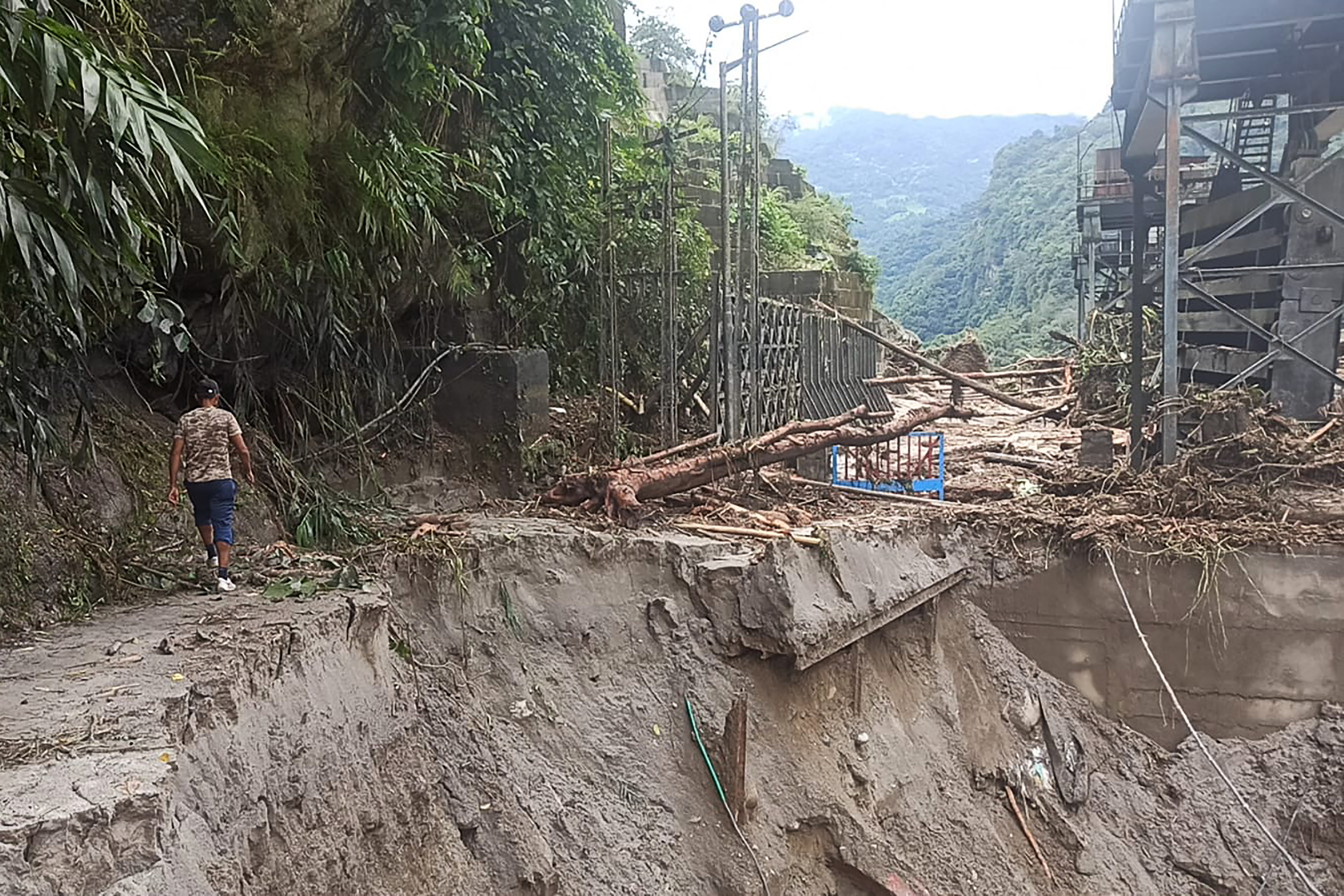 A man walks along a destroyed road near the damaged Teesta V power plant