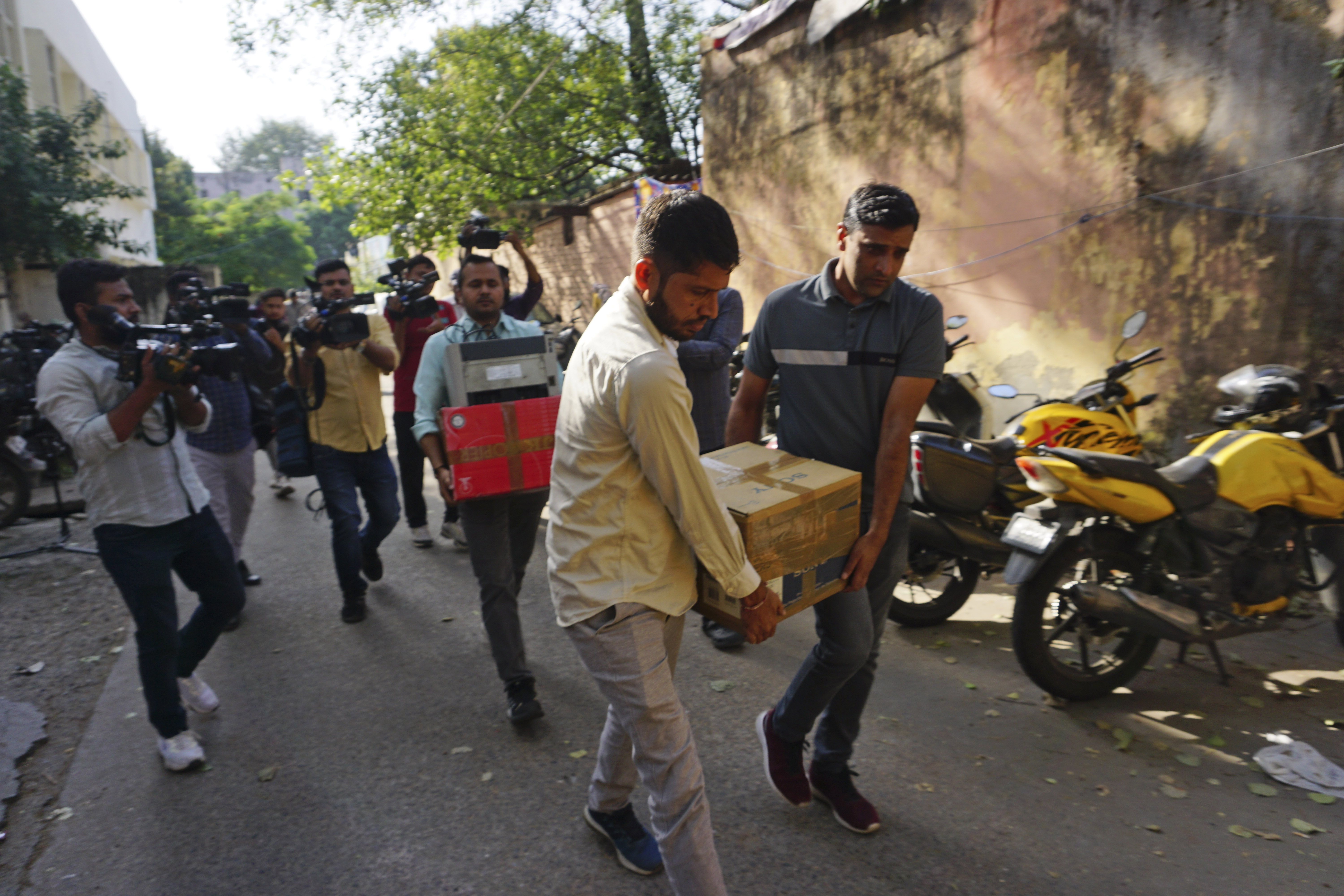 Security officers carry boxes of material confiscated after a raid at the office of NewsClick in New Delhi, India, Tuesday, Oct. 3, 2023. Indian police raided the offices of the news website that's under investigation for allegedly receiving funds from China, as well as the homes of several of its journalists, in what critics described as an attack on one of India's few remaining independent news outlets.