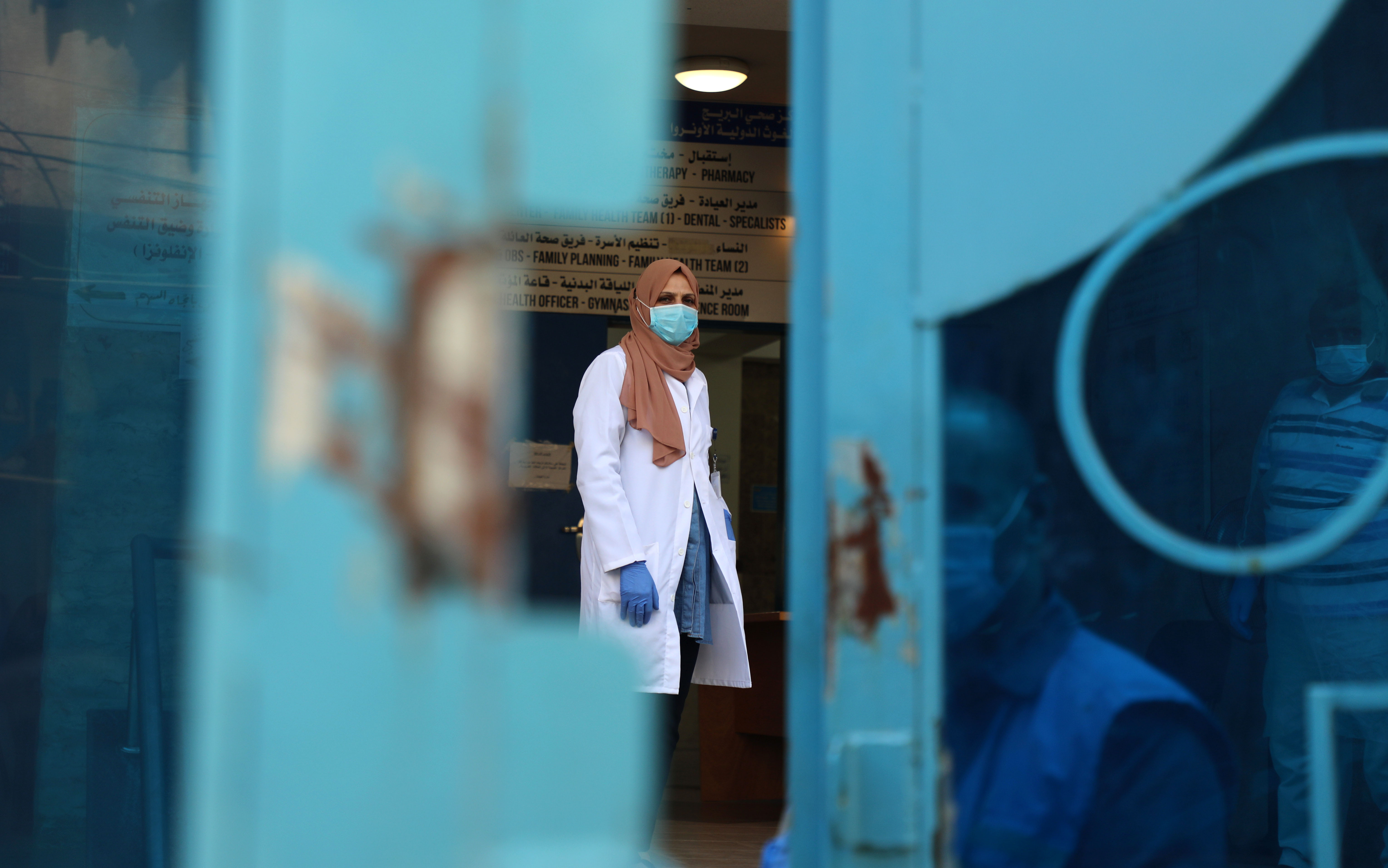 Palestinian UN doctor mask-clad due to the Covid-19 coronavirus stands behind a door at a clinic in Bureij refugee camp central of Gaza Strip