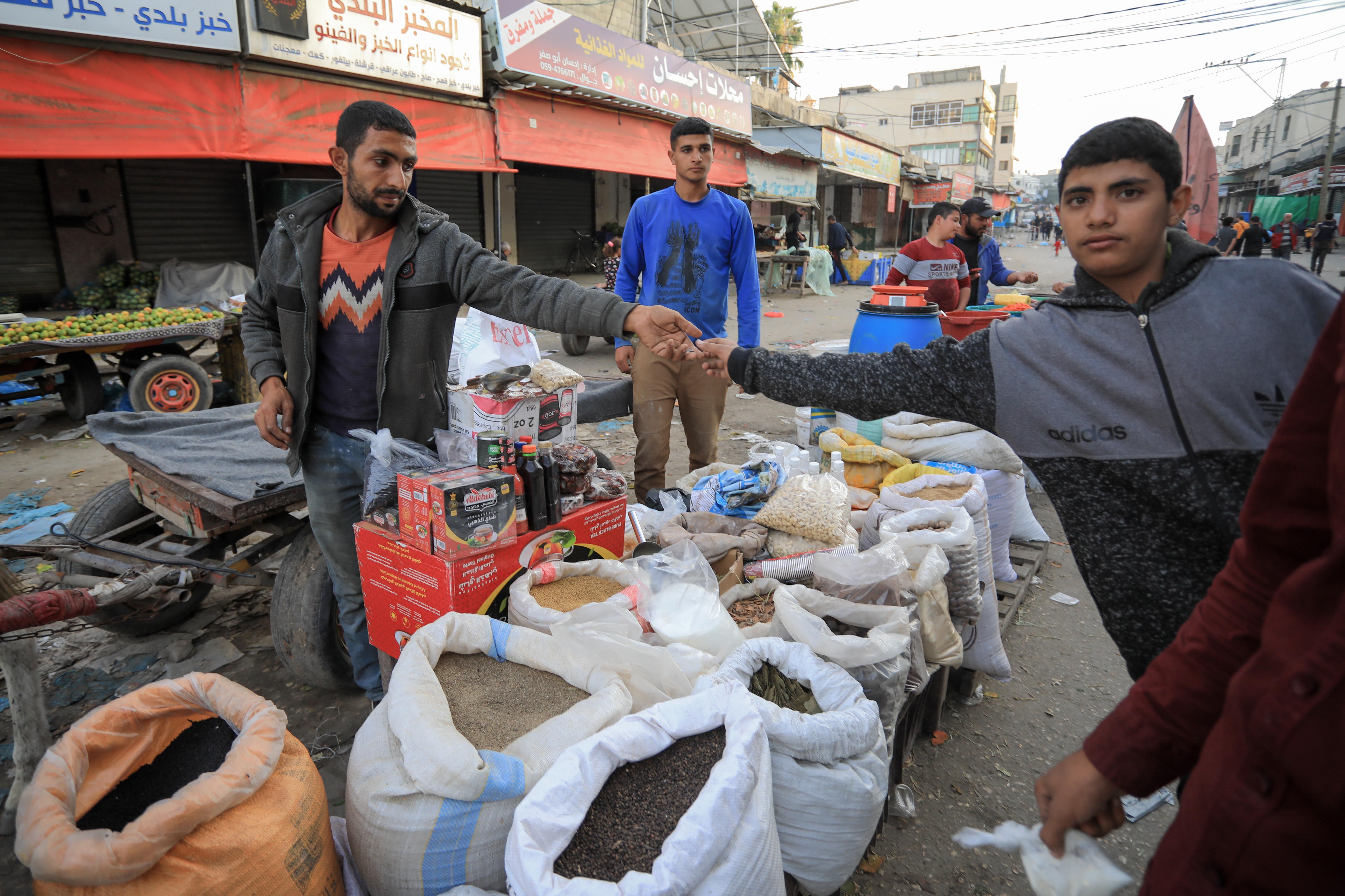 Mohammed Yasser Abu Amra (left) receives money from a shopper in the Deir al-Balah market