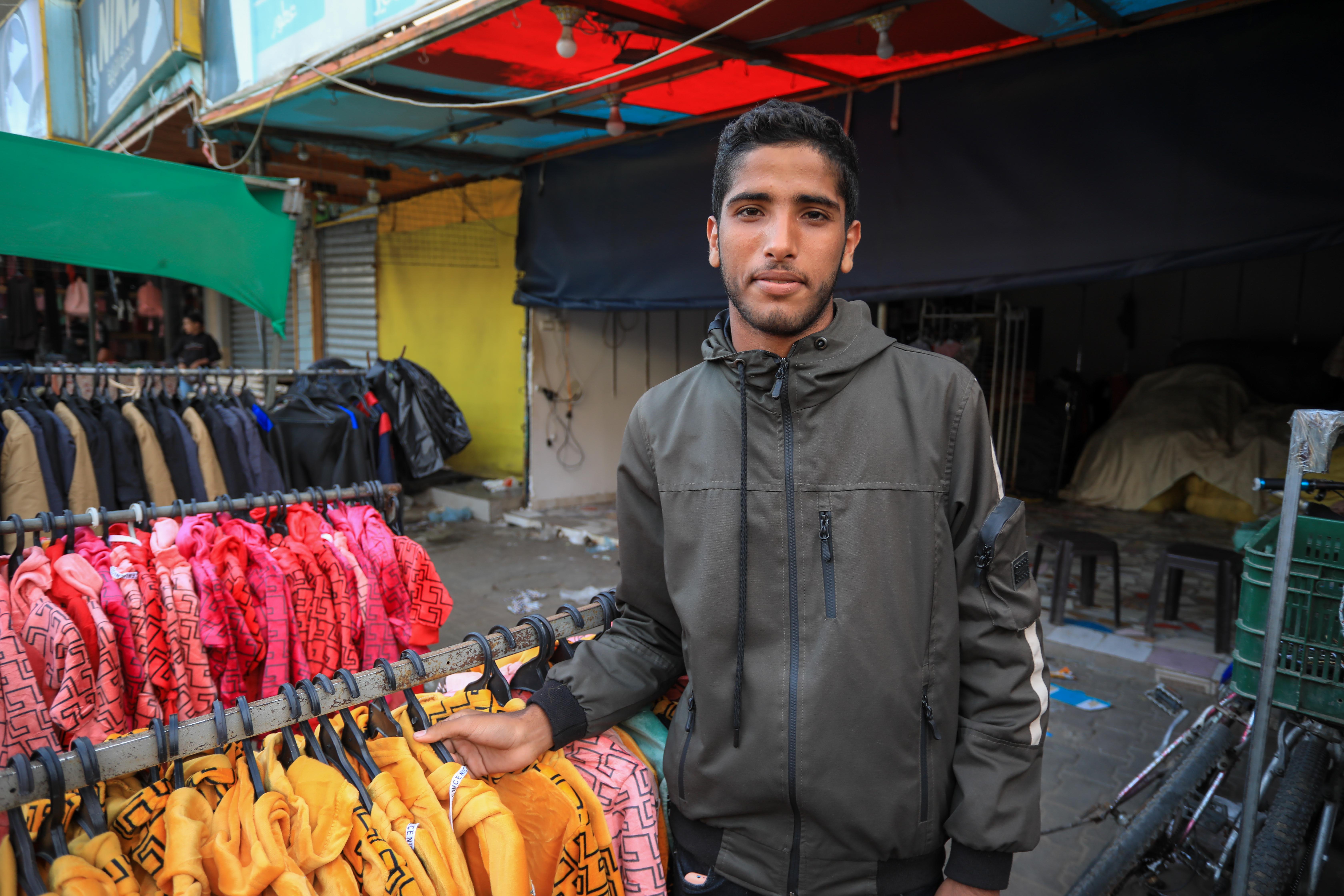 Ali Abulnaja sells clothes in a stall in the Deir al-Balah marketplace