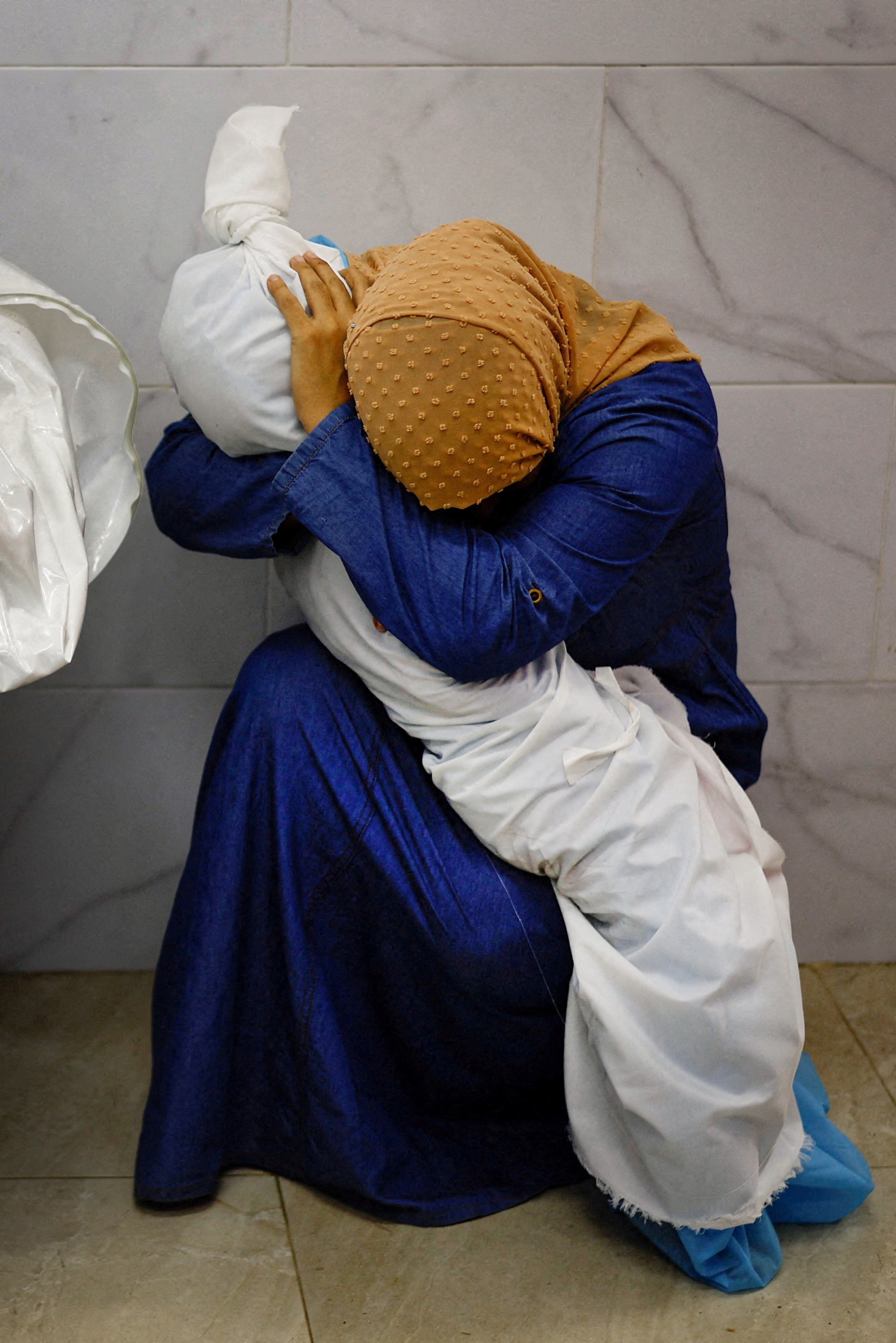 Palestinian woman Inas Abu Maamar, 36, embraces the body of her 5-year-old niece Saly, who was killed in an Israeli strike, at Nasser hospital in Khan Younis in the southern Gaza Strip.
