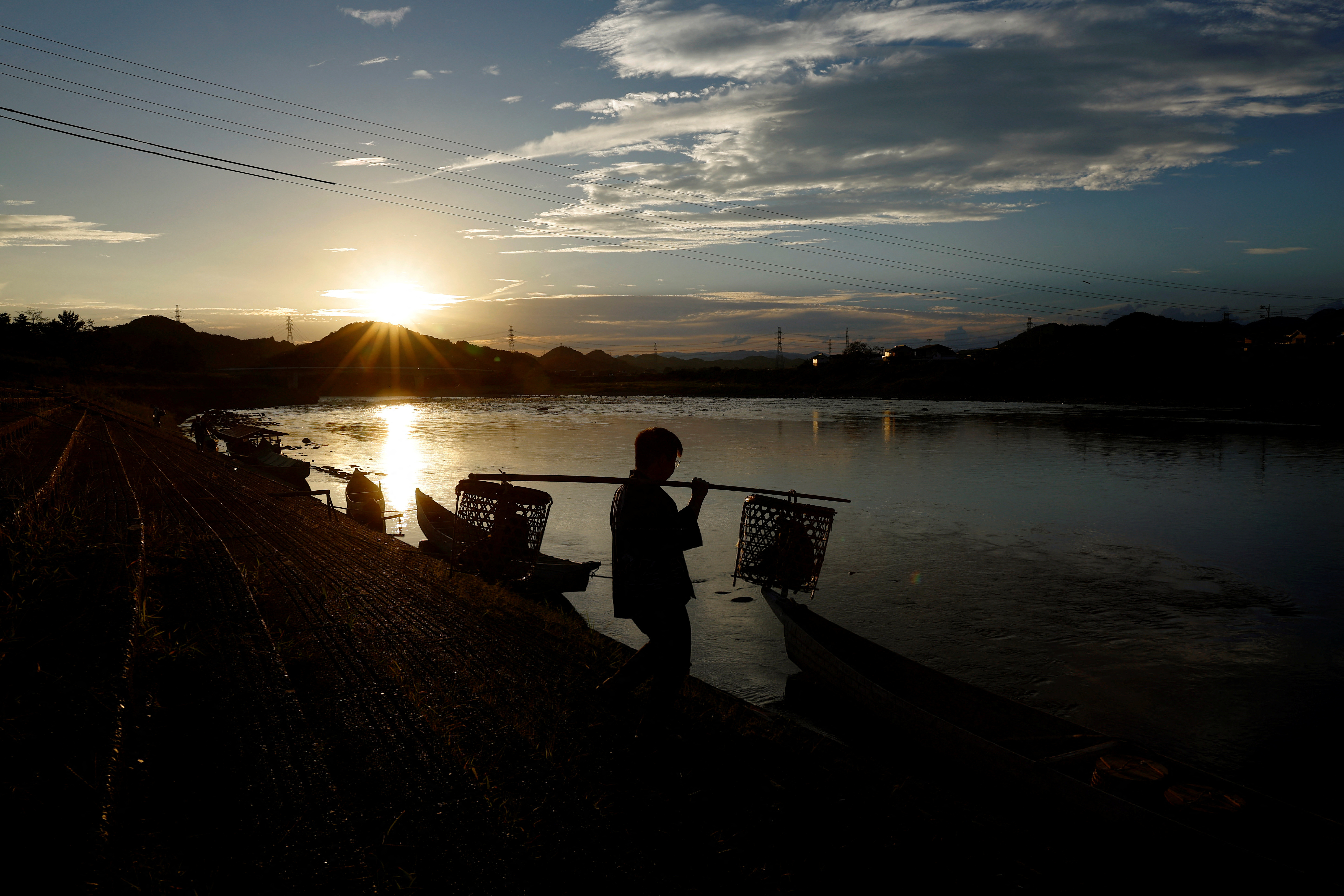 Toichiro, 22, son of cormorant fishing master or usho Youichiro Adachi, 48, carries cormorants in baskets as he prepares for cormorant fishing or ukai, on the Nagara River in Oze, Seki, Japan.