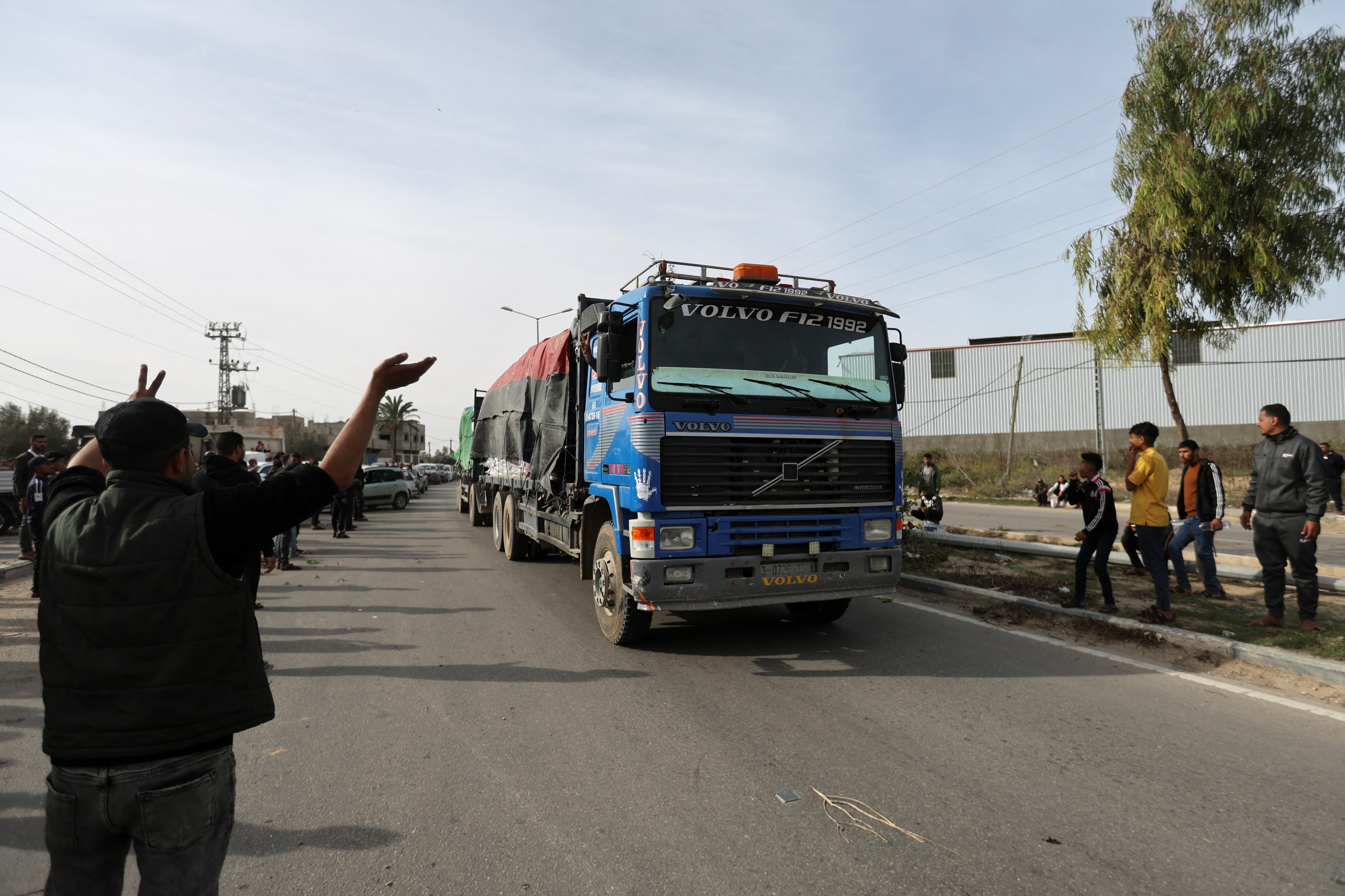 Aid trucks move on a road as Palestinians look on, during a temporary truce between Hamas and Israel, in Rafah, in the southern Gaza Strip November 25