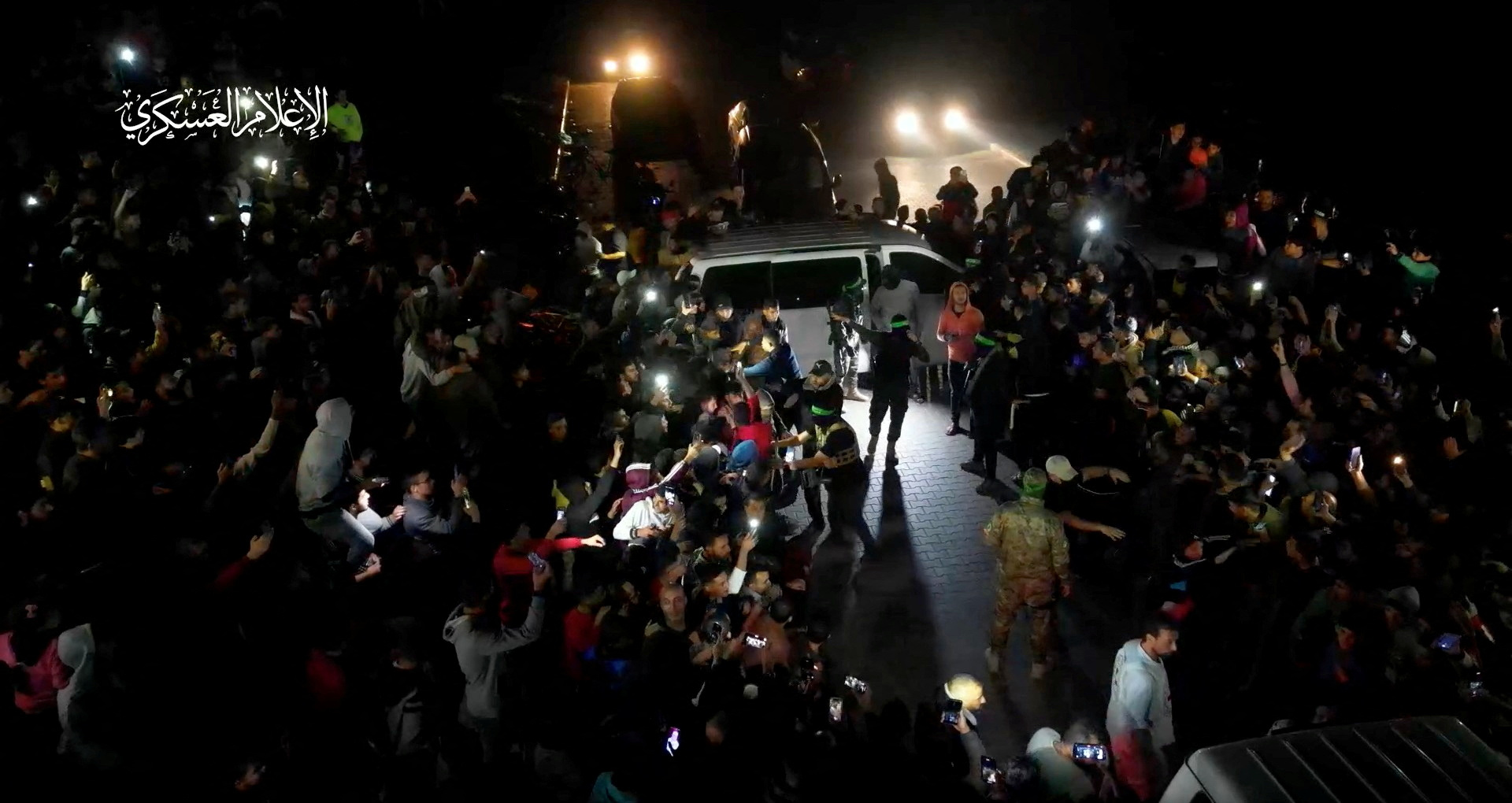 People gather as hostages who were abducted by Hamas gunmen during the October 7 attack on Israel are handed over by Hamas militants to the International Red Cross, as part of a hostages-prisoners swap deal between Hamas and Israel amid a temporary truce, in an unknown location in the Gaza Strip.