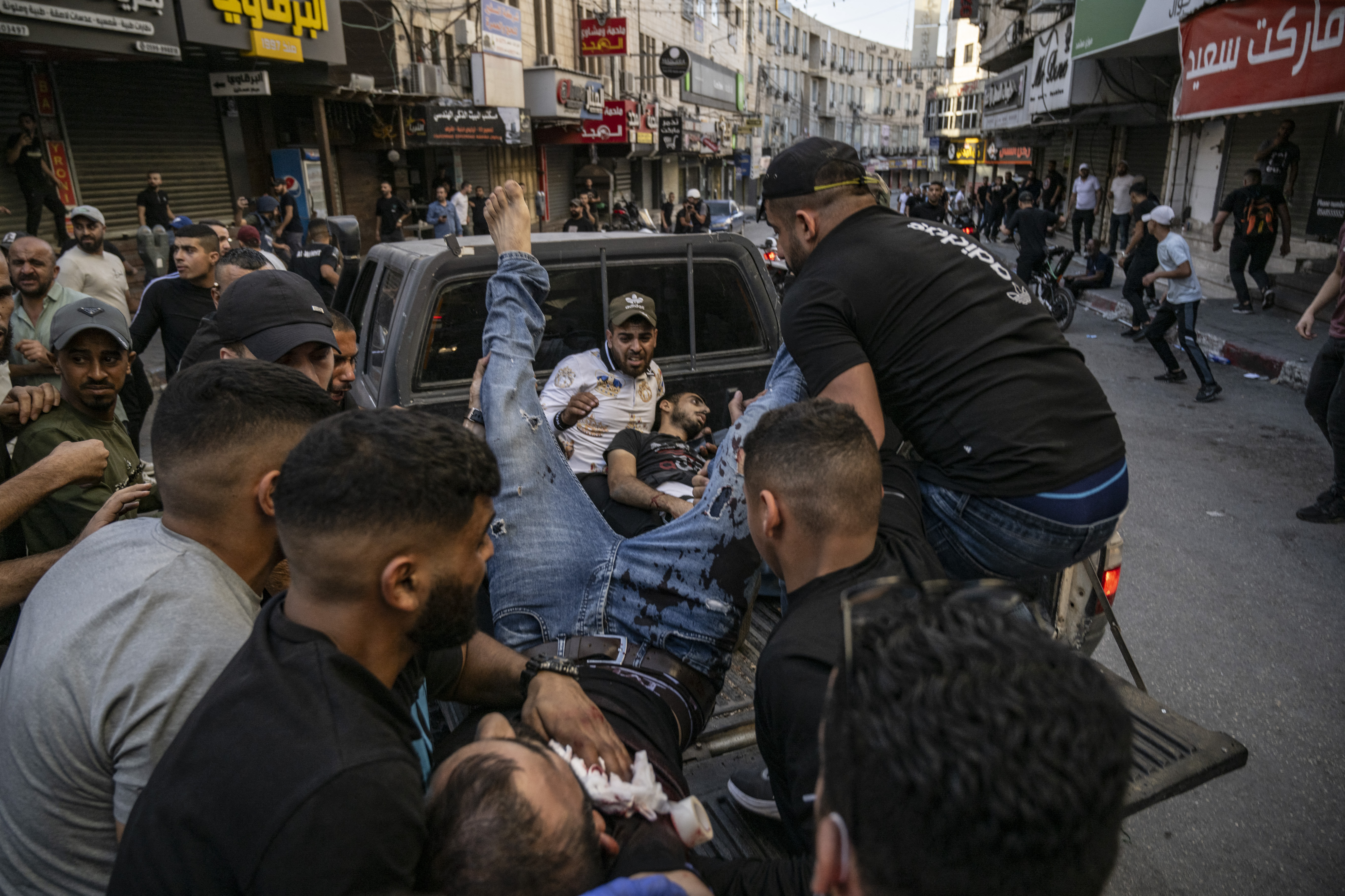Two injured men are carried away in the back of a pick-up truck after being reportedly shot by Israeli forces during confrontations with them in the occupied West Bank city of Jenin.