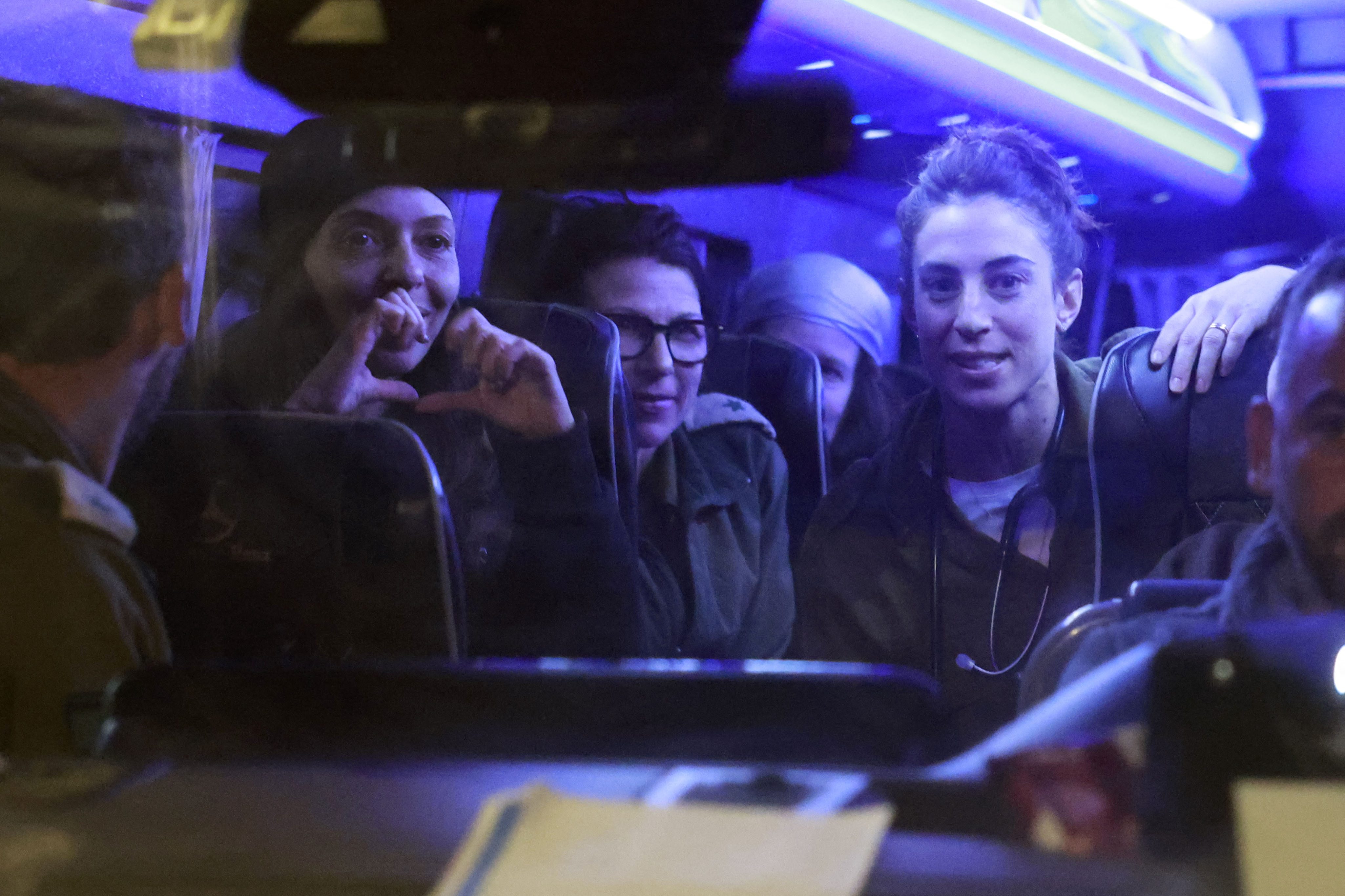 A newly release Israeli hostage gestures as she sits among soldiers and other hostages upon arrival at Ofakim army base in southern Israel.