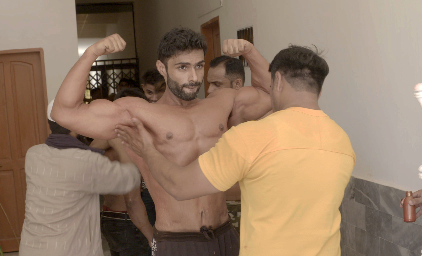 A bodybuilders getting tanning gel applied on his muscles on competition day
