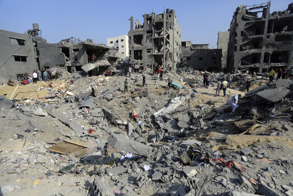 Palestinians wander among the rubble of buildings destroyed in an Israeli airstrike