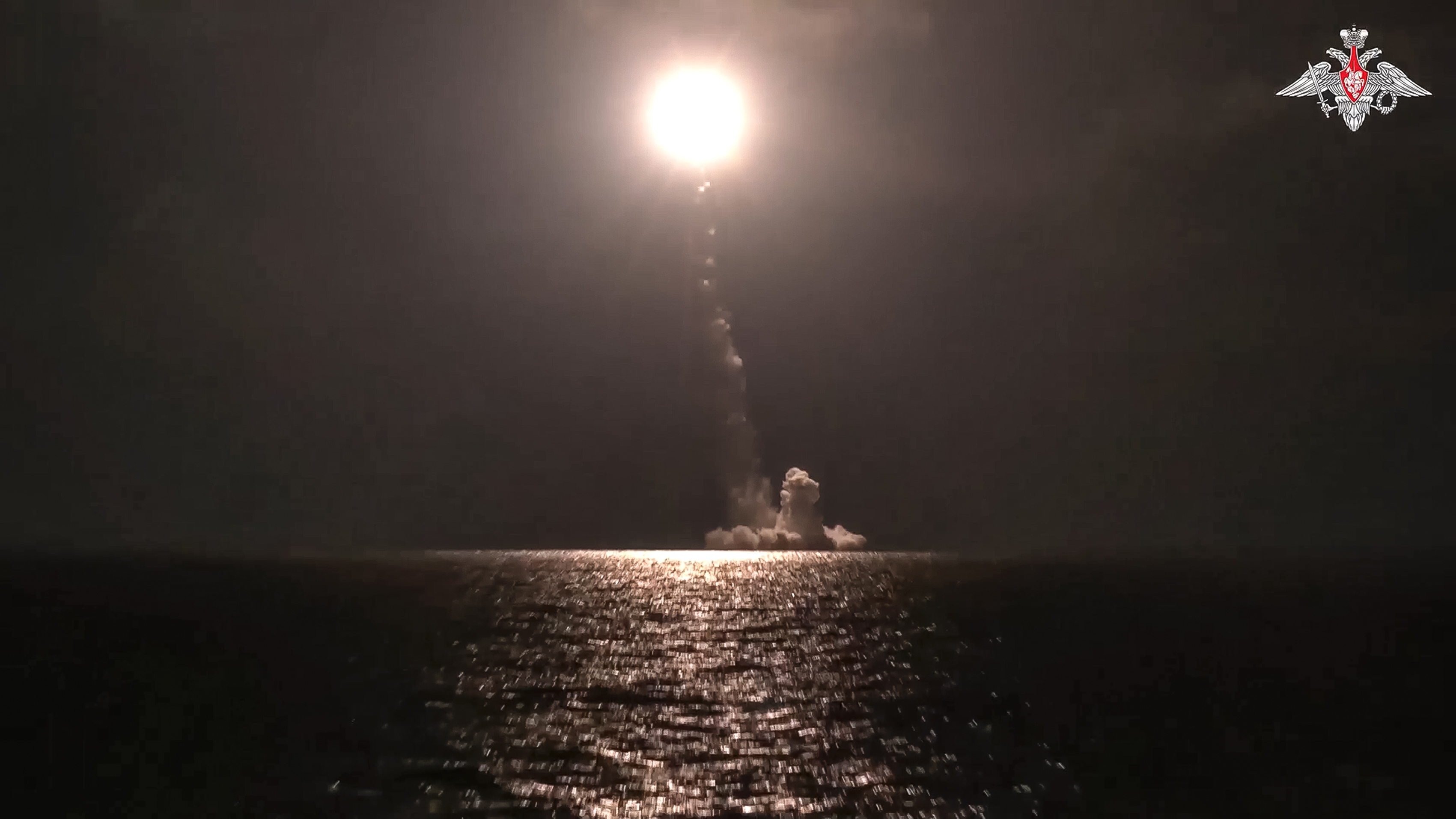 A photo released by Russian Defense Ministry Press Service shows a Bulava intercontinental ballistic missile being fired from a submarine. It is dark, The streak of the missile and a white/orange explosion can be seen.