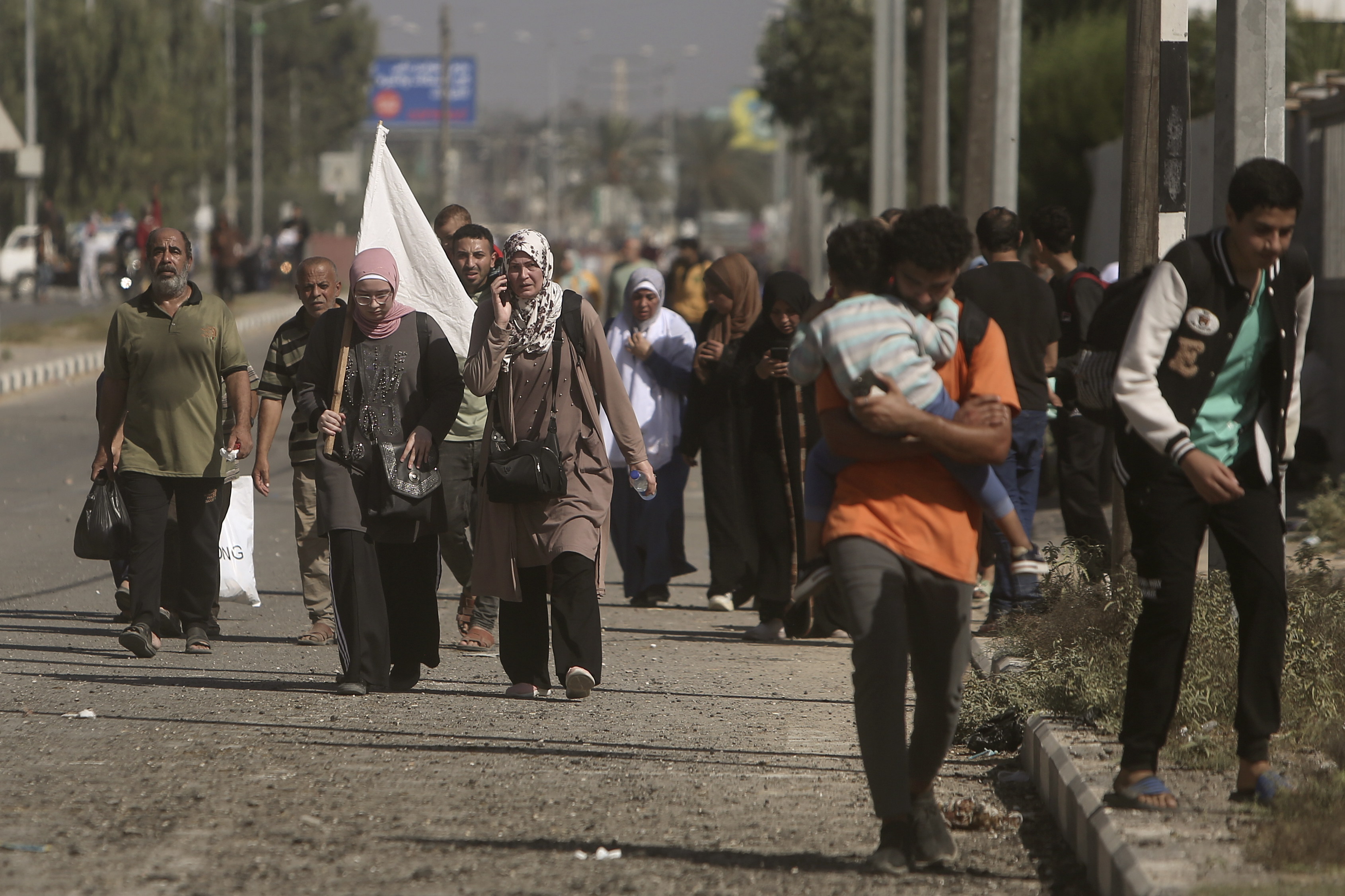 A woman carries a white flag to prevent being shot, as Palestinians flee Gaza City to the southern Gaza Strip on Salah al-Din street in Bureij.