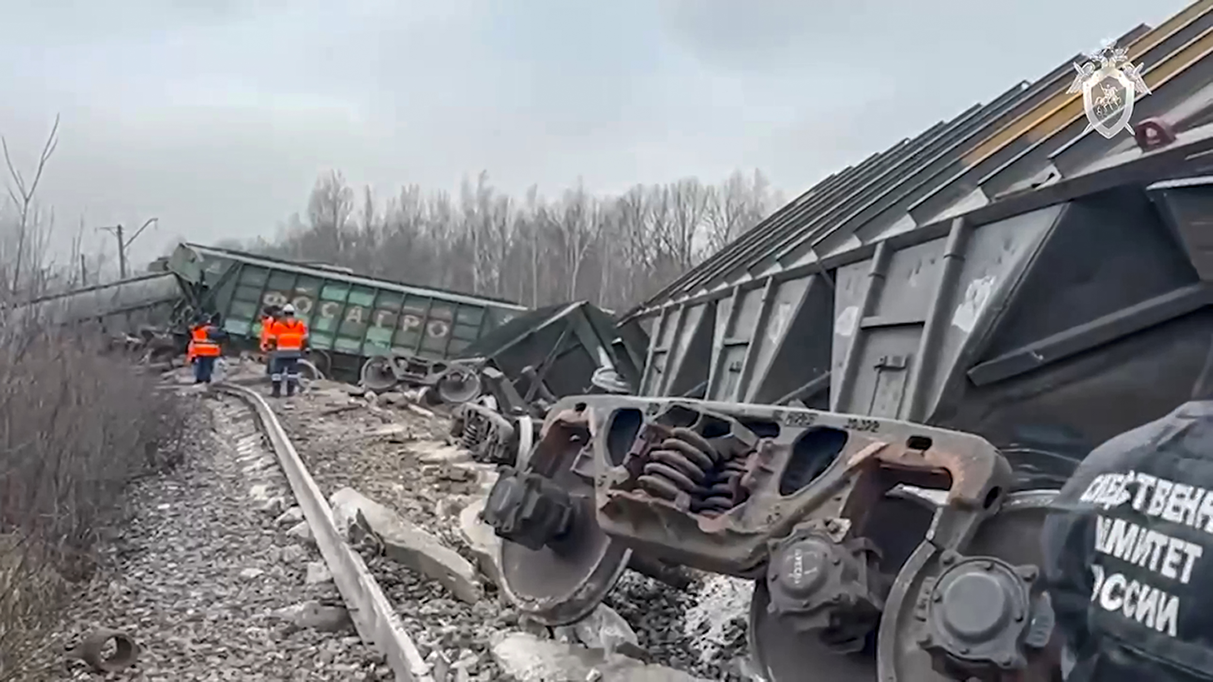 Train carriages lying alongside the tracks with workers in high-vis jackets standing further down the line