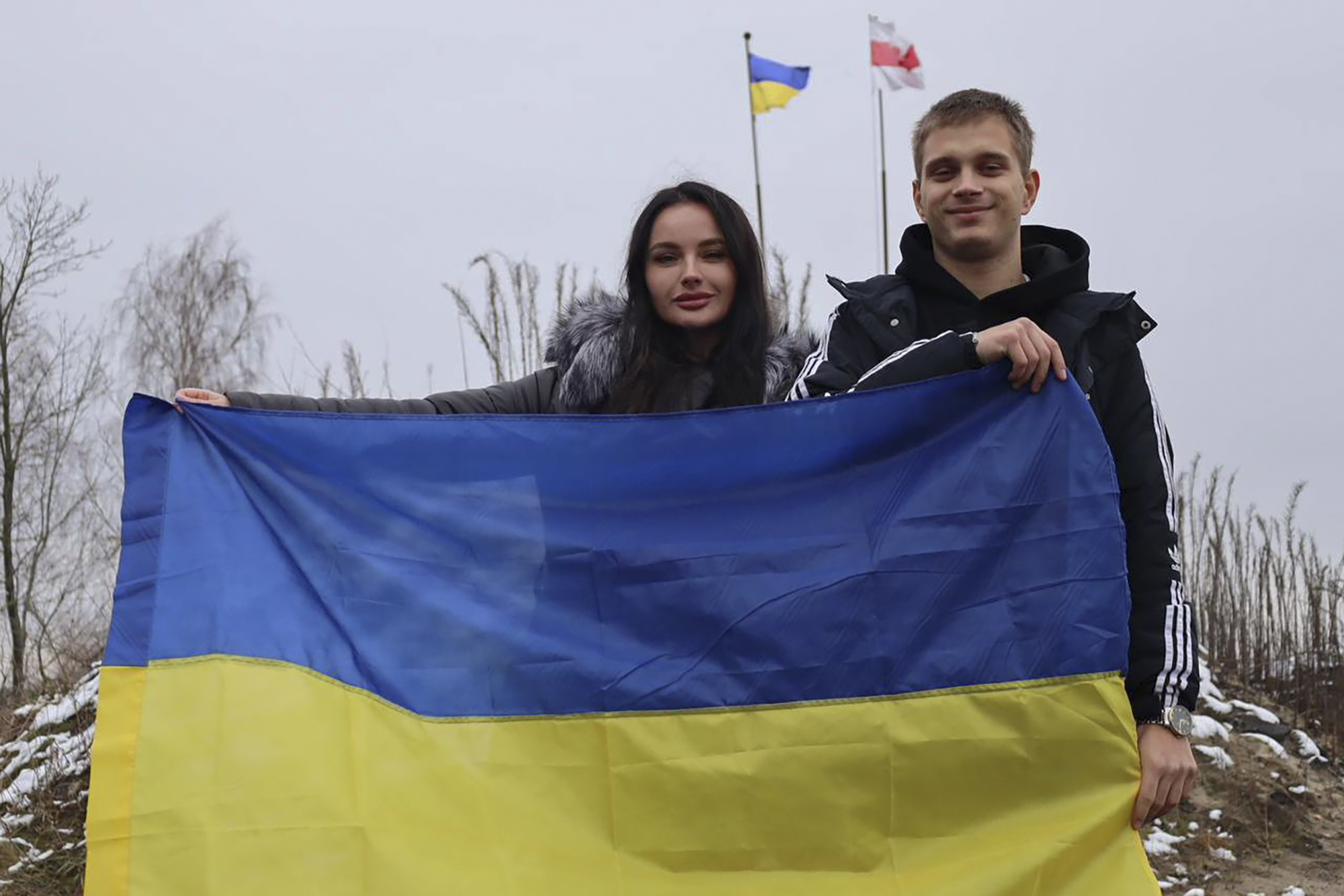 Ukrainian teenager Bohdan Yermokhin, right, holds the Ukraine flag on the Ukraine-Belarus border