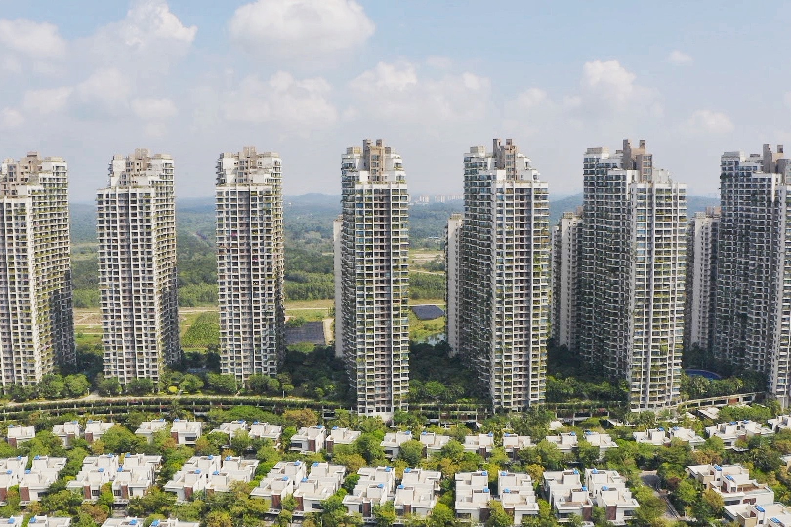 A row of high rise apartment blocks with a street of two storey houses in front.