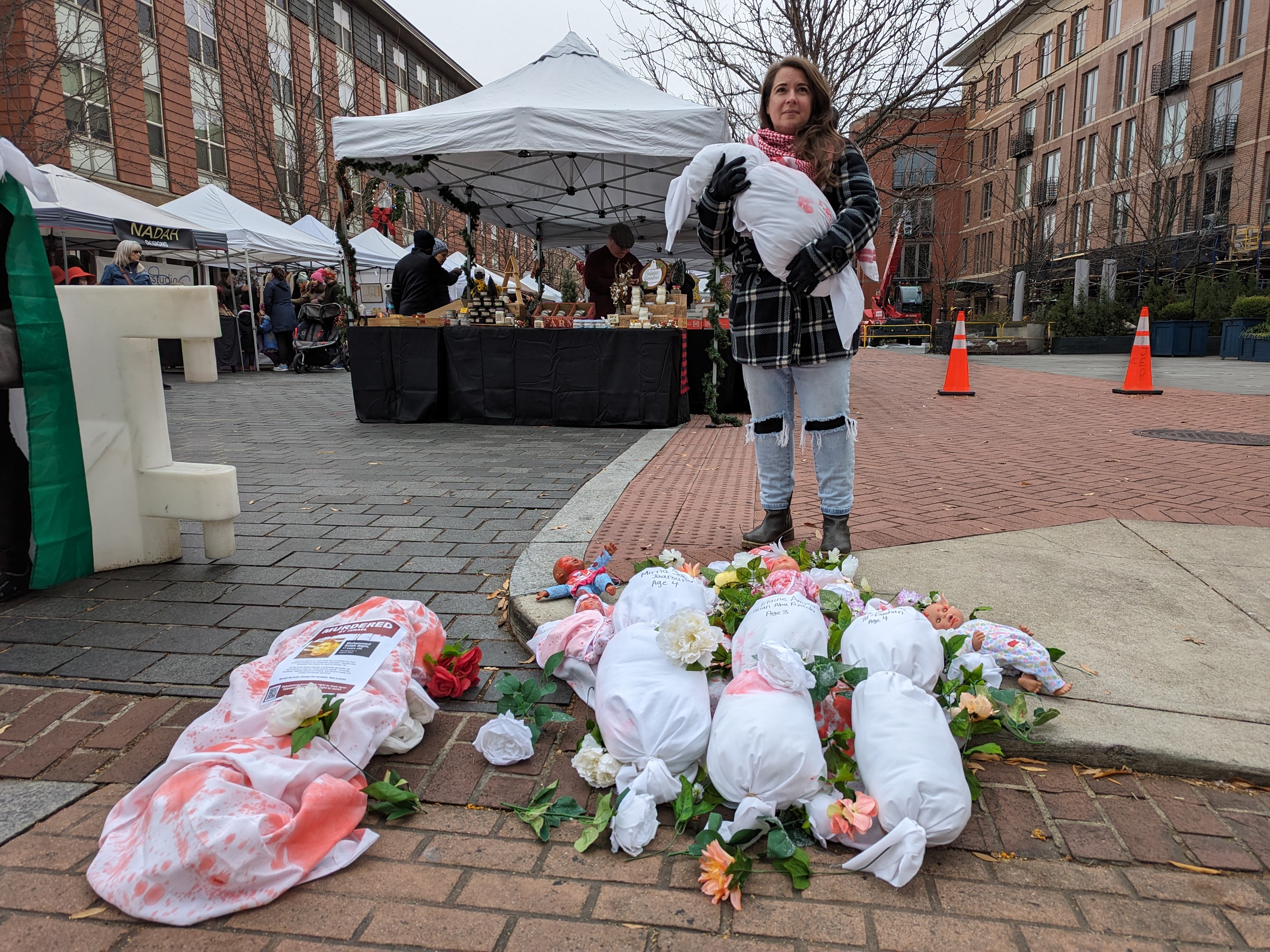Woman golds shrouds depicting body bags of children in Gaza