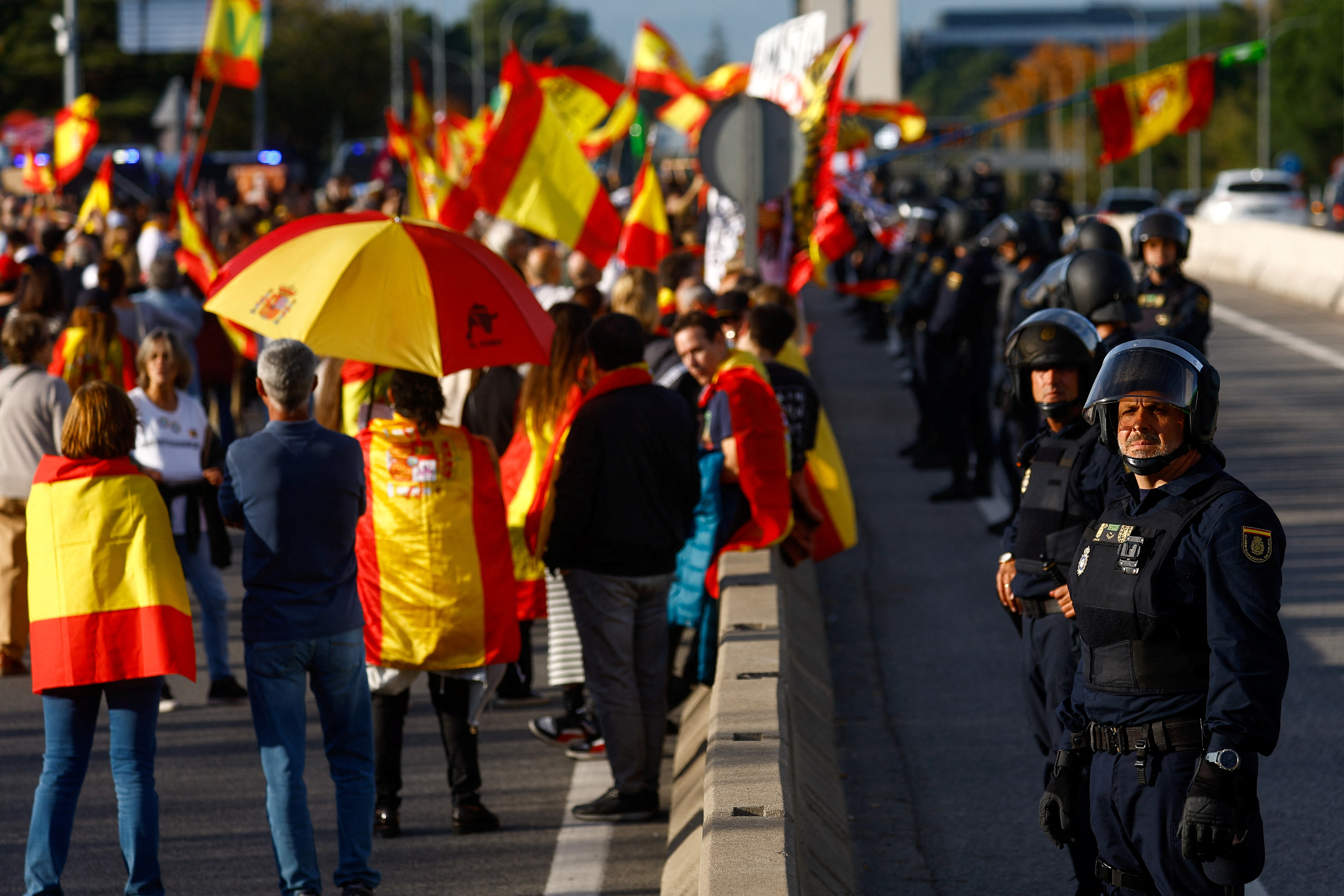 Police officers stand guard as people block the road leading to Moncloa Palace [Reuters/Susana Vera]