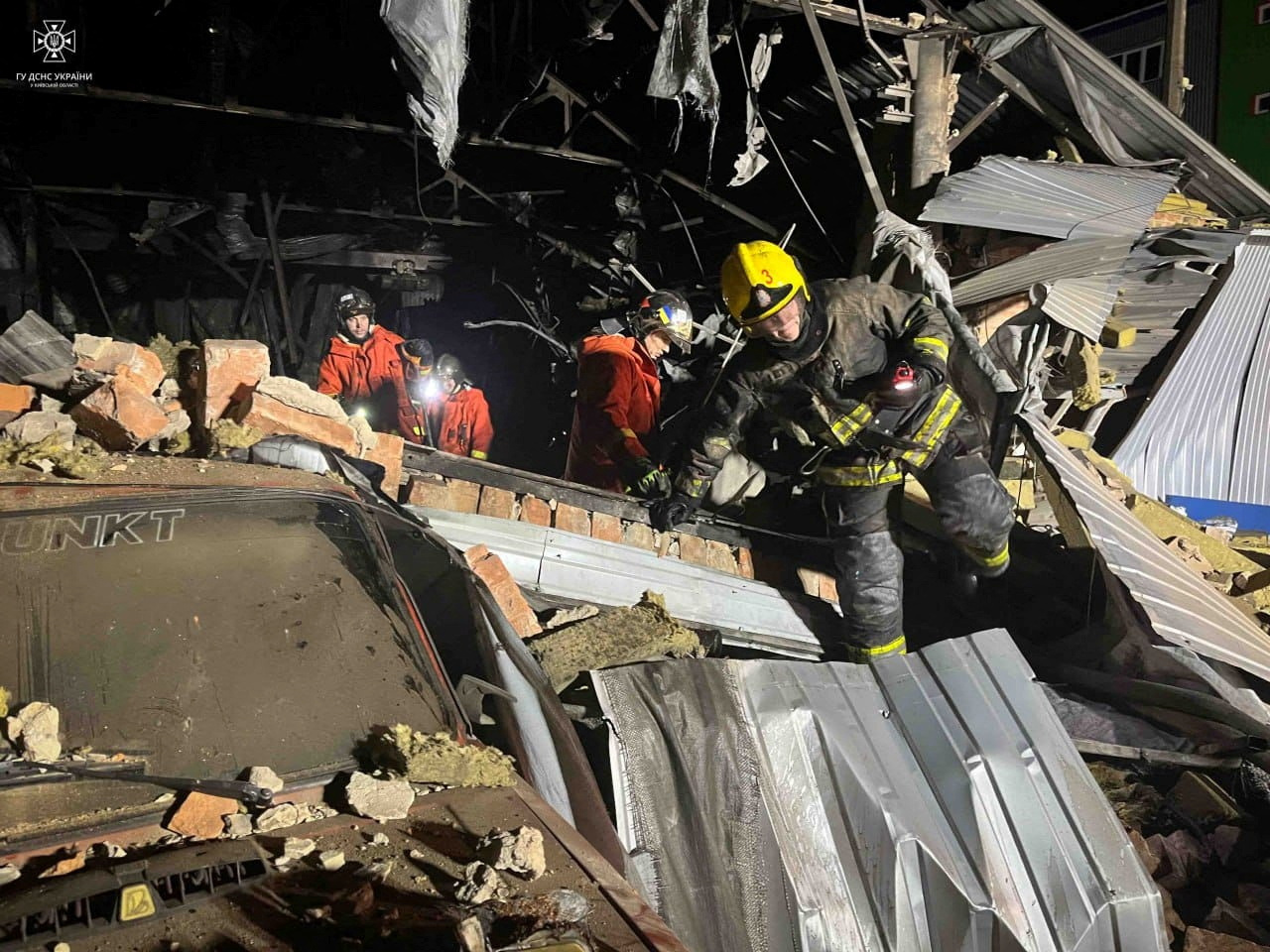 A firefighter working at the site of a warehouse damaged in a Russian drone attack. He is scrambling over debris.