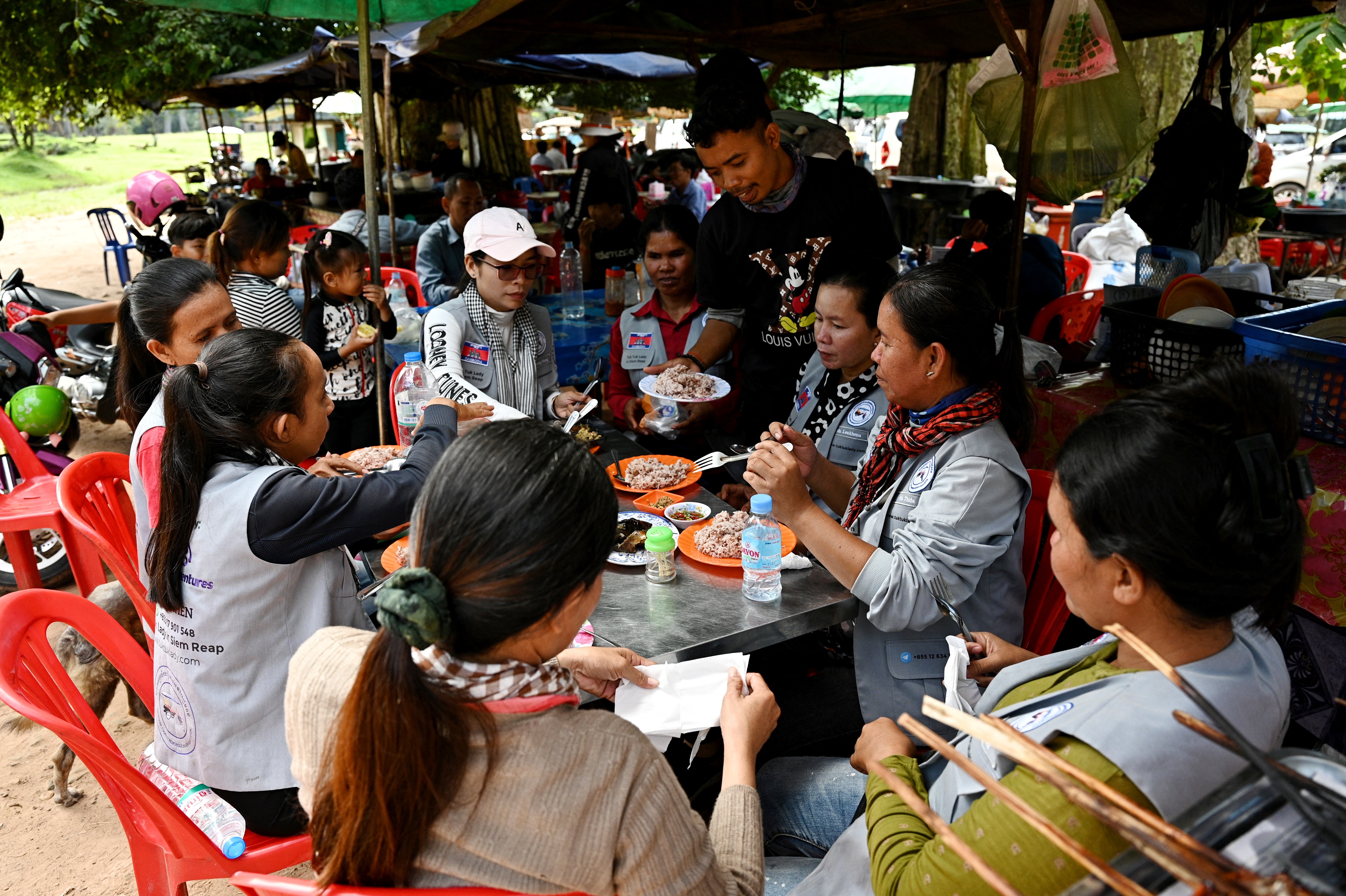 This photo taken on November 17, 2023 shows female Tuk Tuk drivers eating lunch near the terrace of the elephants at the Angkor complex in Siem Reap province.