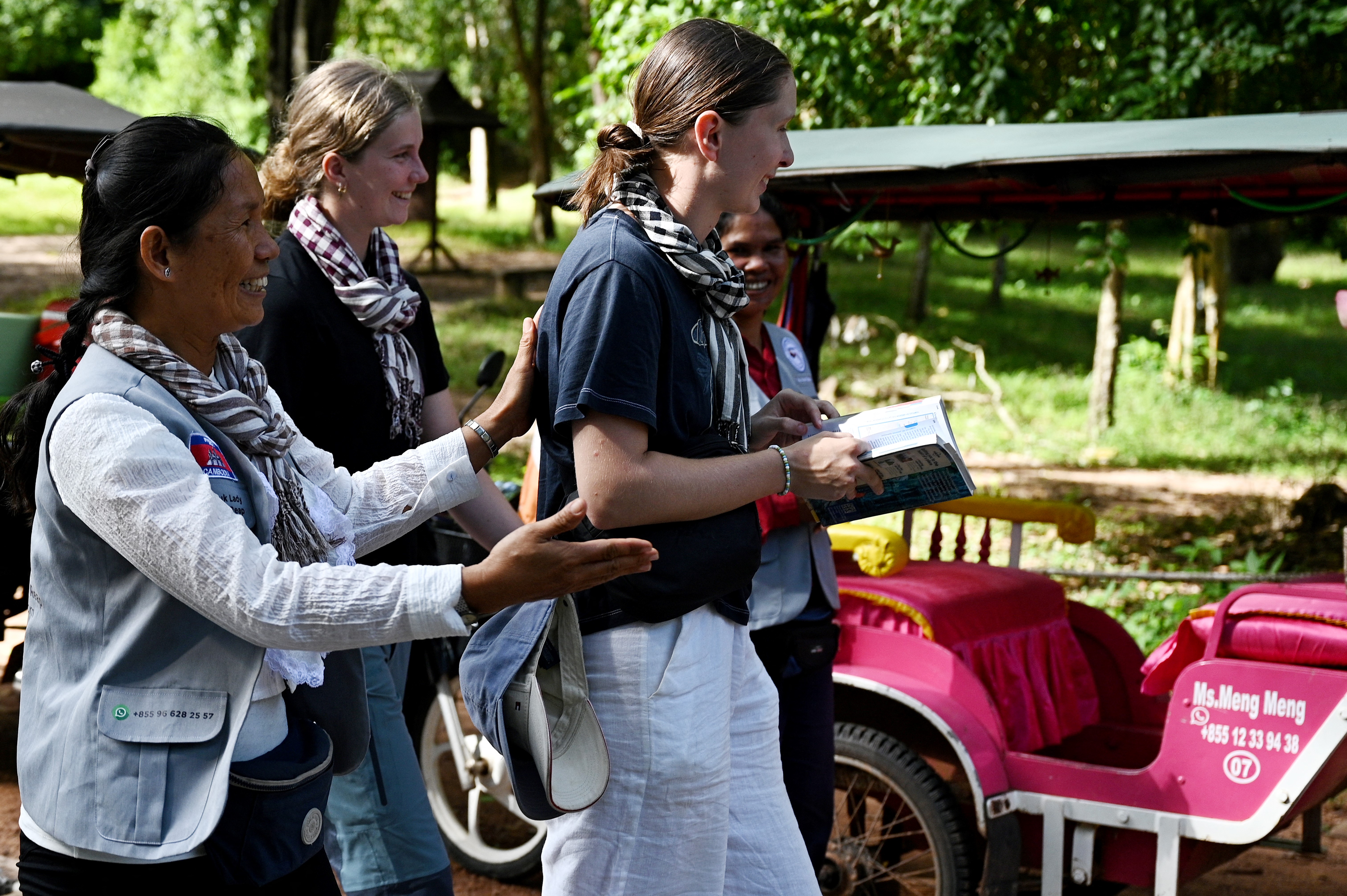 This photo taken on November 17, 2023 shows female Tuk Tuk driver Kim Sokleang guiding her passengers to her Tuk Tuk near the Angkor Thom south gate at the Angkor complex in Siem Reap province.
