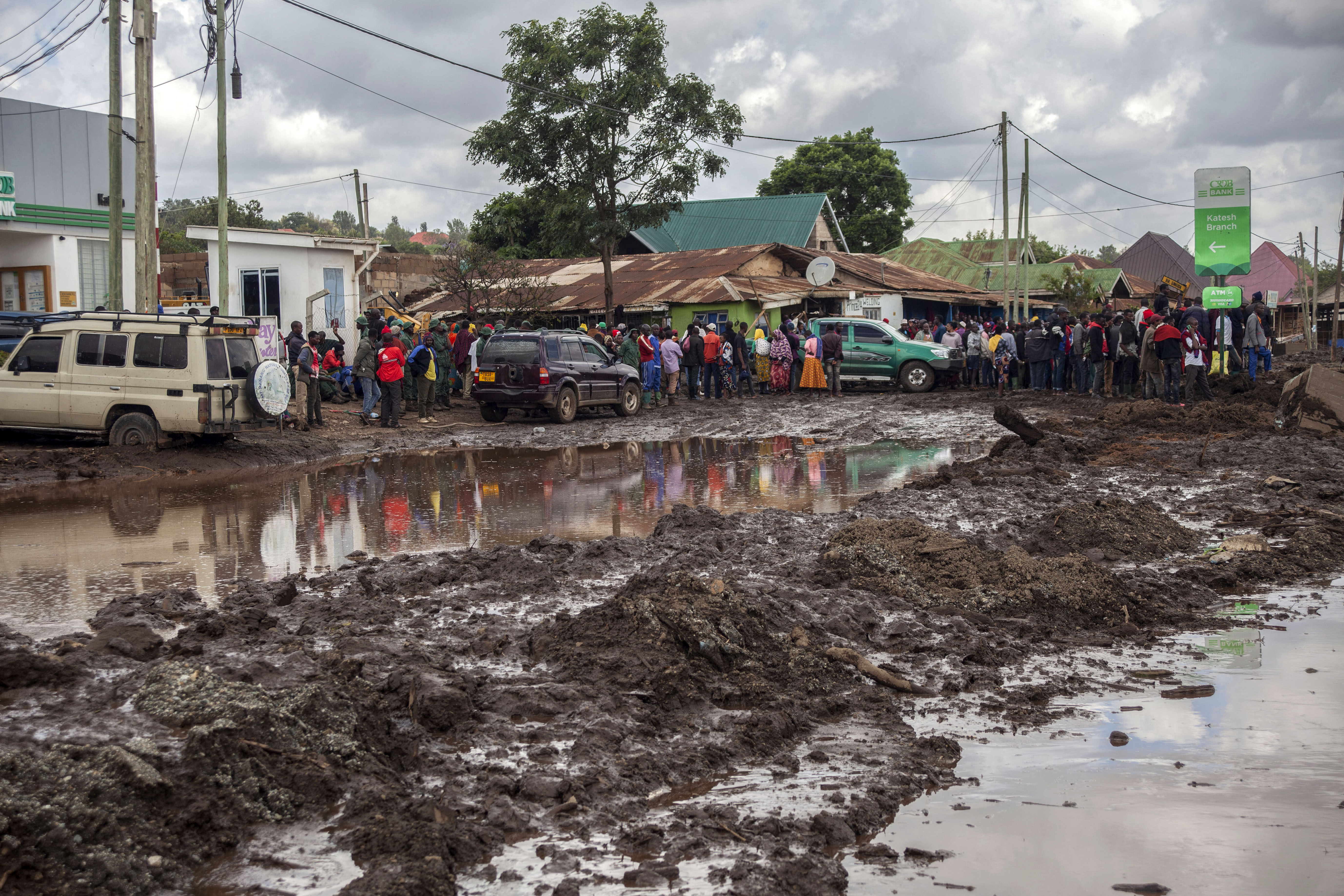 People gather to assess damages at a street covered on mud following landslides and flooding triggered by heavy rainfall in Katesh, Tanzania.