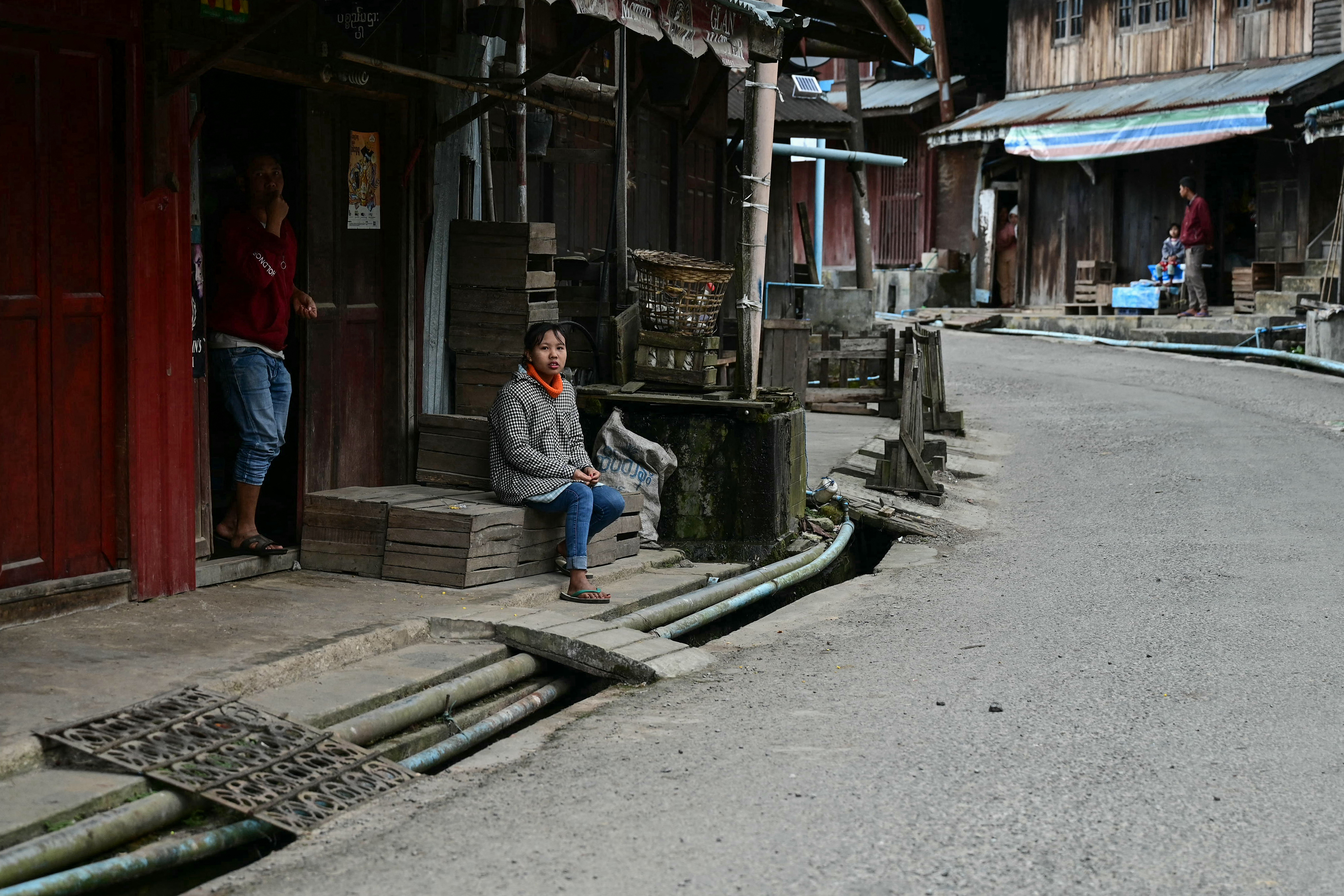 This photo taken on December 12, 2023 shows residents looking out from their home along a quiet street in Namhsan Township amid clashes between ethnic minority armed group Ta'ang National Liberation Army (TNLA) and Myanmar's military in northern Shan State.