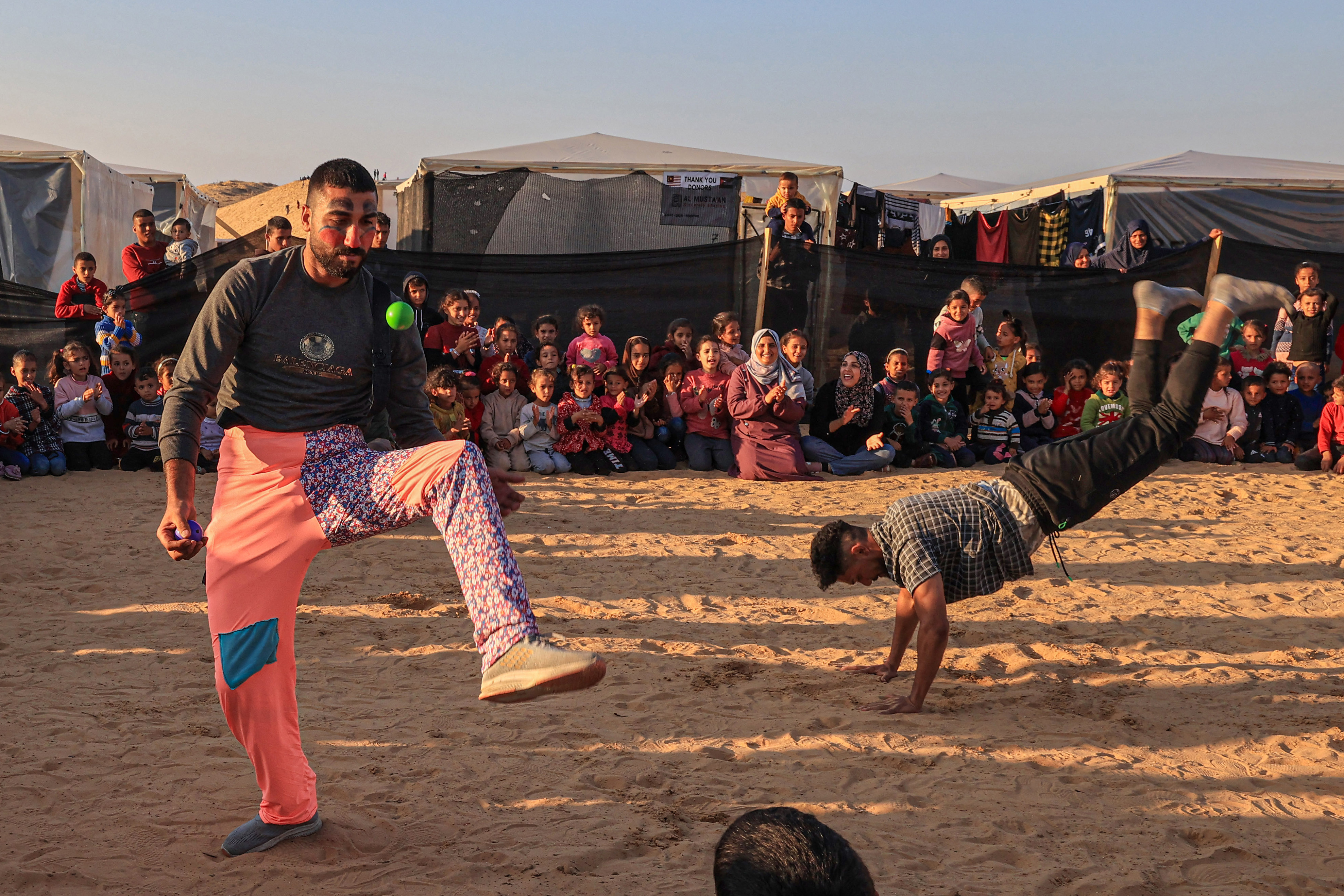 Men dressed as clowns perform for children participating in an activity aimed to support their mental health, amid continuing battles between Israel and the militant group Hamas, in Rafah in the southern Gaza Strip.