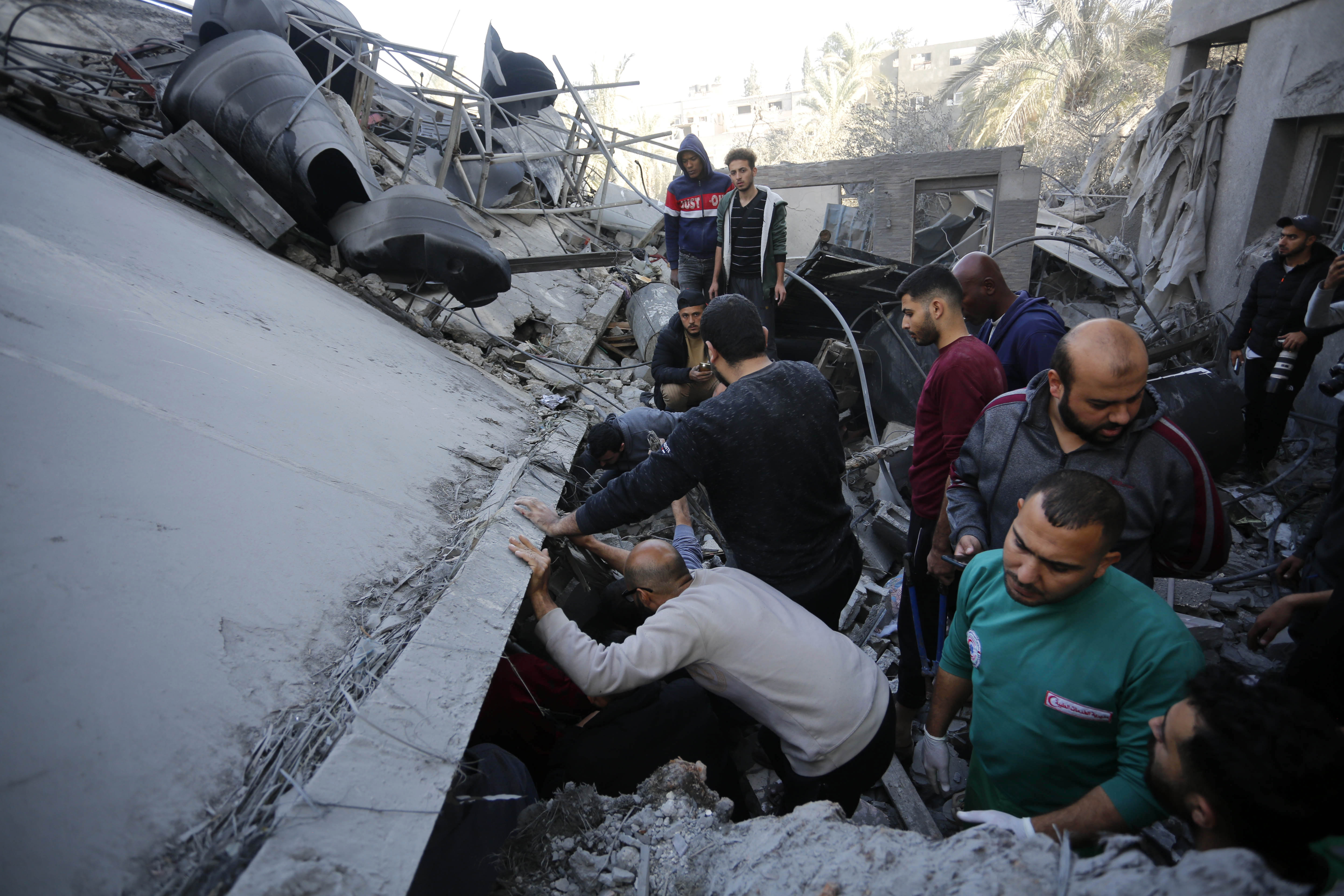 Residents and civil defense teams conduct a search and rescue operation among demolished buildings after Israeli attacks in Deir Al-Balah, Gaza.