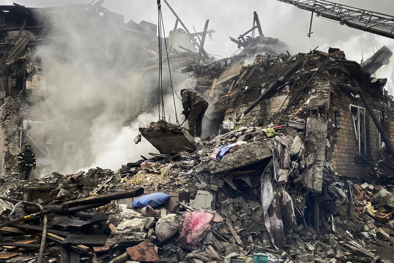 Rescuers work at the scene of a building hit by a Russian attack in eastern Ukraine. The building has been reduced to a large pile of rubble.