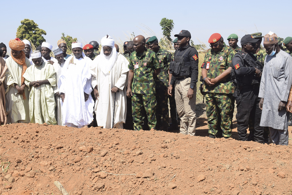 People gather around a grave for victims of a drone attack