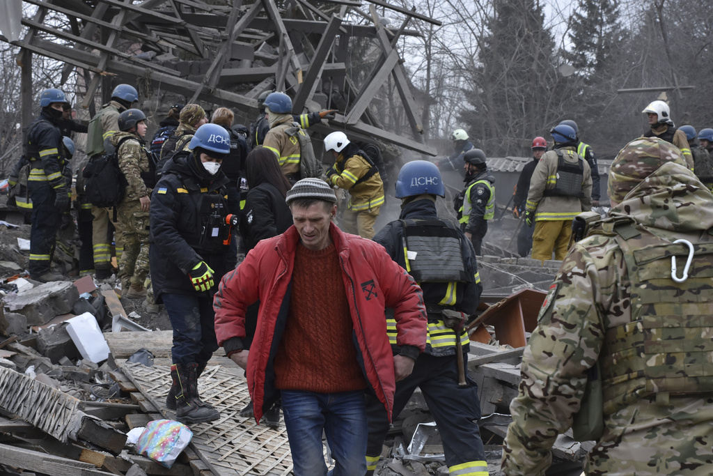 People clear debris from the site of a Russian strike