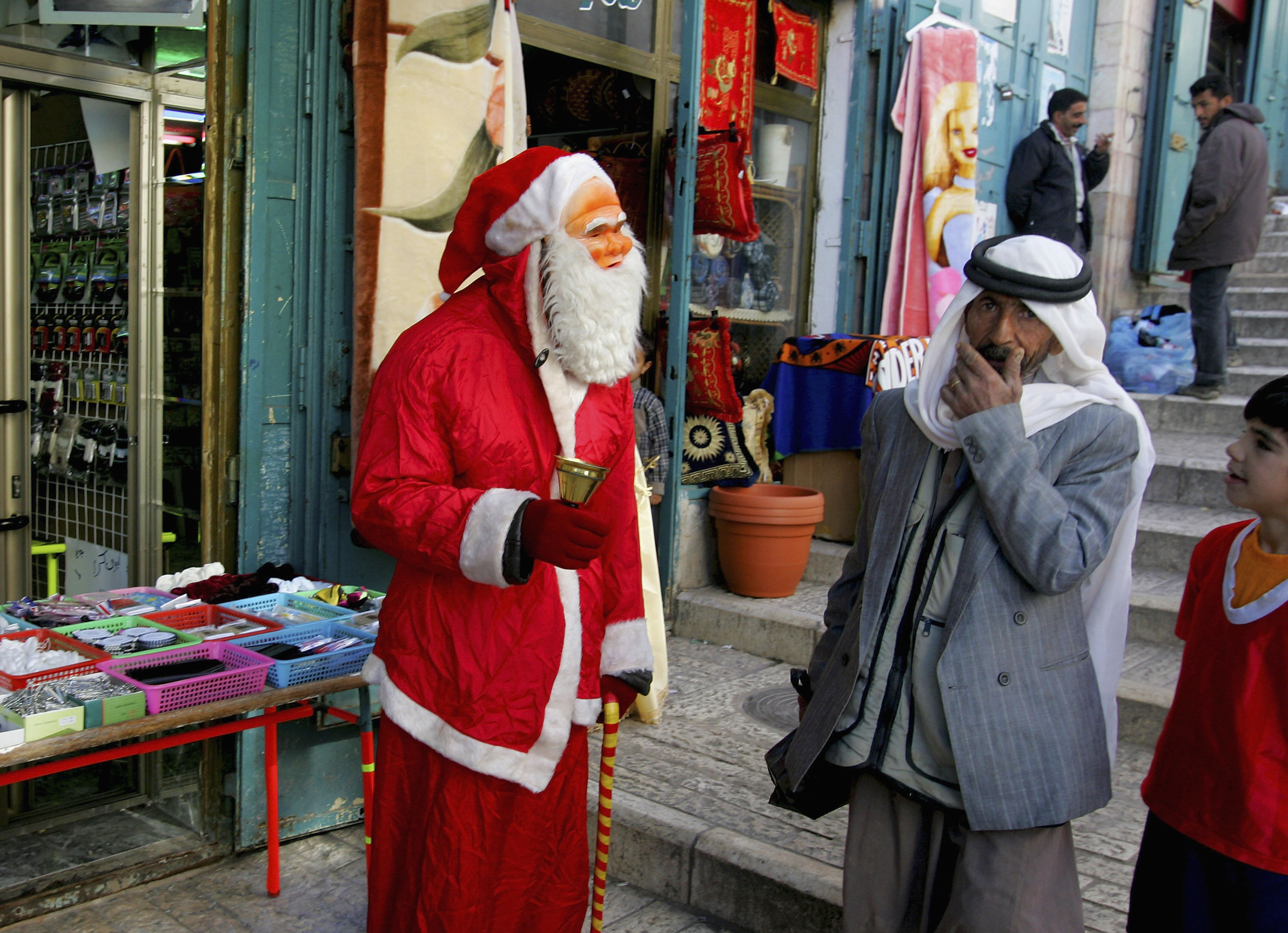 Hassan Abu Hillail, a 40-year-old Palestinian Christian shopkeeper, who dresses up as Santa Claus to try and drum up business, greets Palestinians passing his shop near the Church of the Nativity, the traditional birthplace of Jesus. 