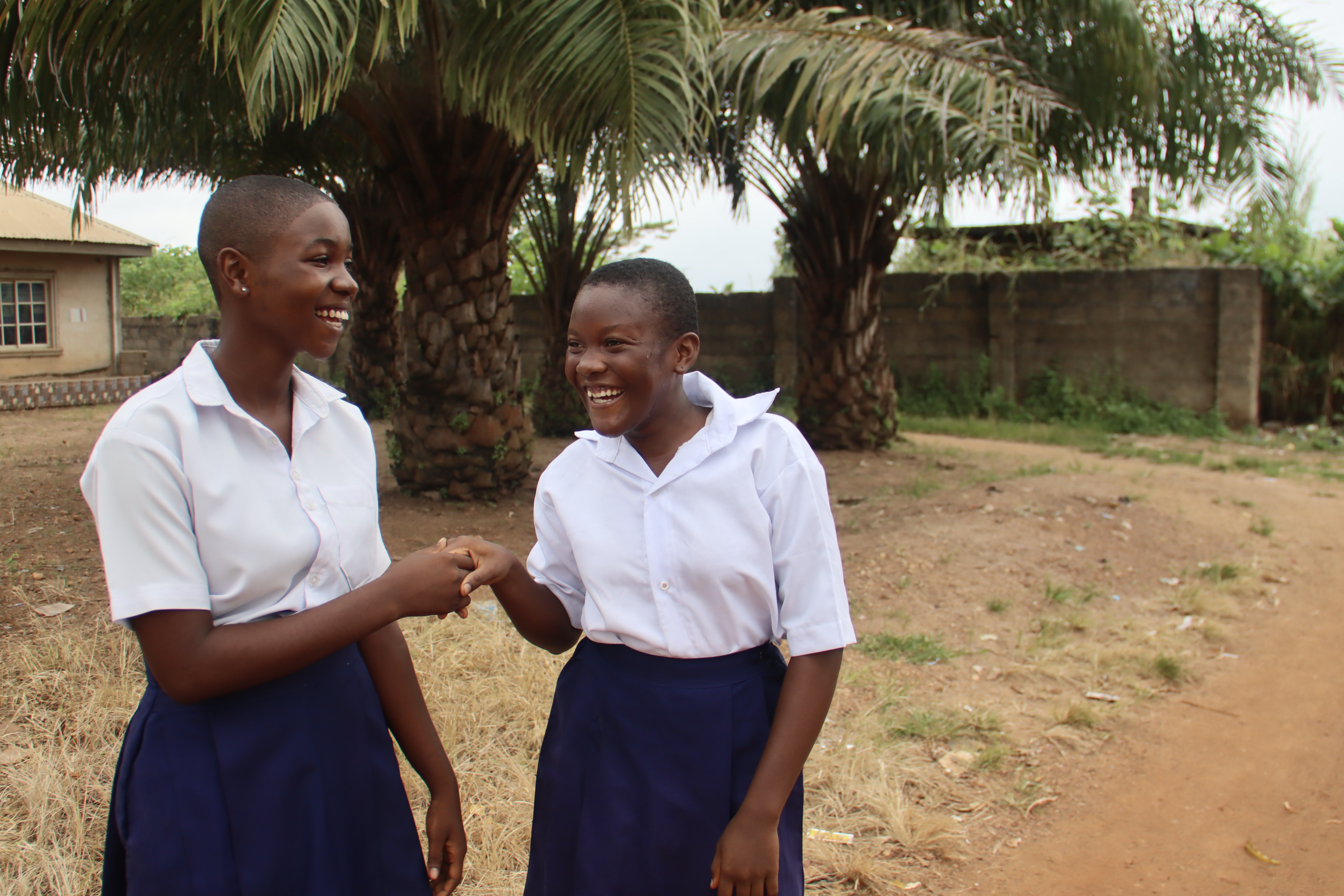 A photo of Blessing (right) and Rebecca shaking hands outside.