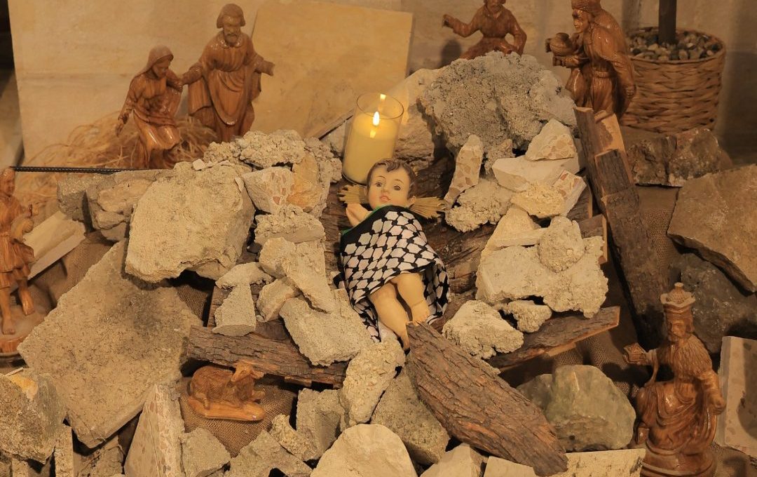 Closeup of Baby Jesus doll wrapped in Palestinian keffiyeh in the rubble manger