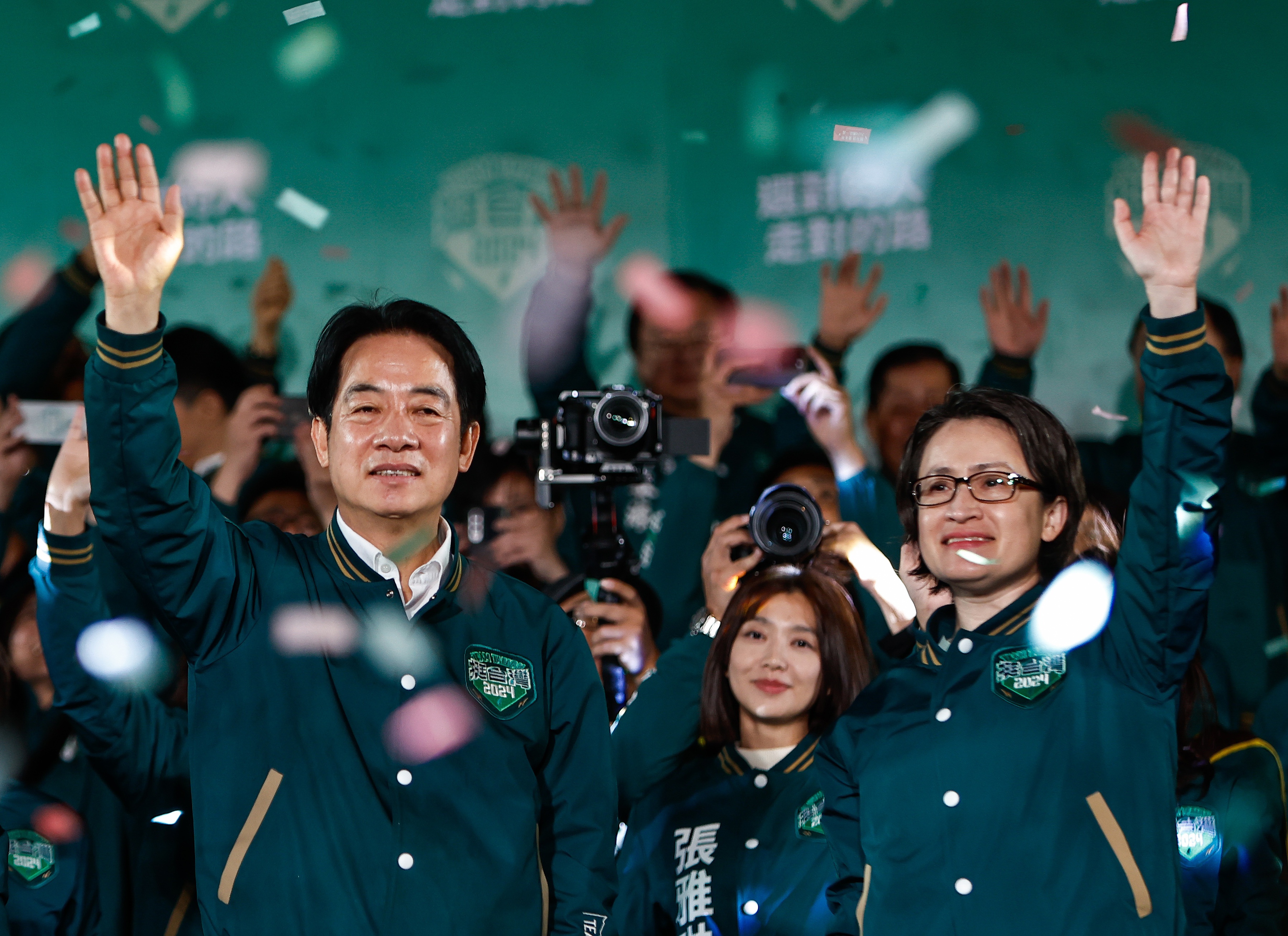 Lai Ching-te and Hsiao Bi-khim wave and smile after their election victory. Colourful ticker-tape is falling around them
